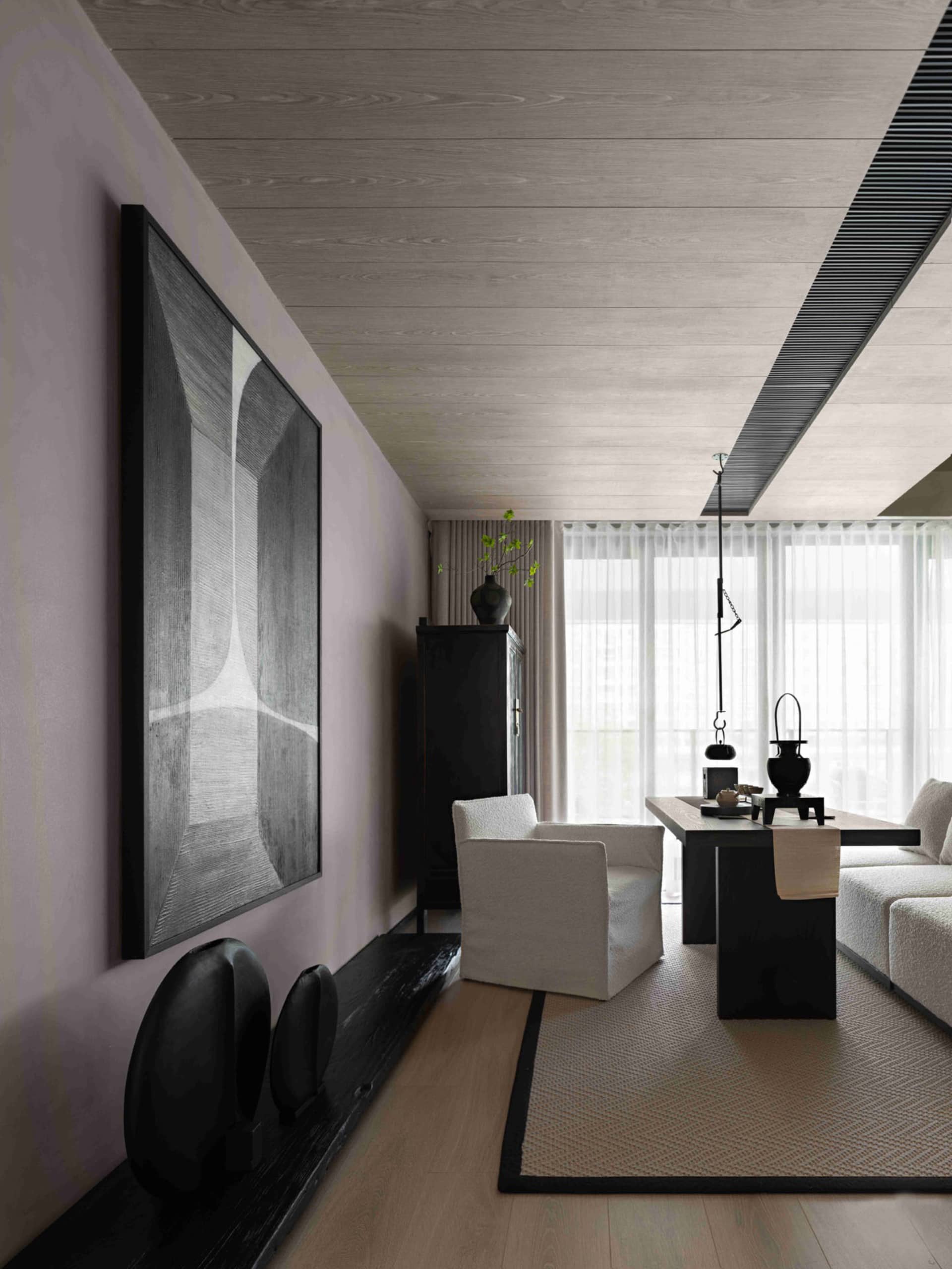 Modern living room featuring wooden flooring, white furniture, and black accents with a large abstract art piece on the wall.