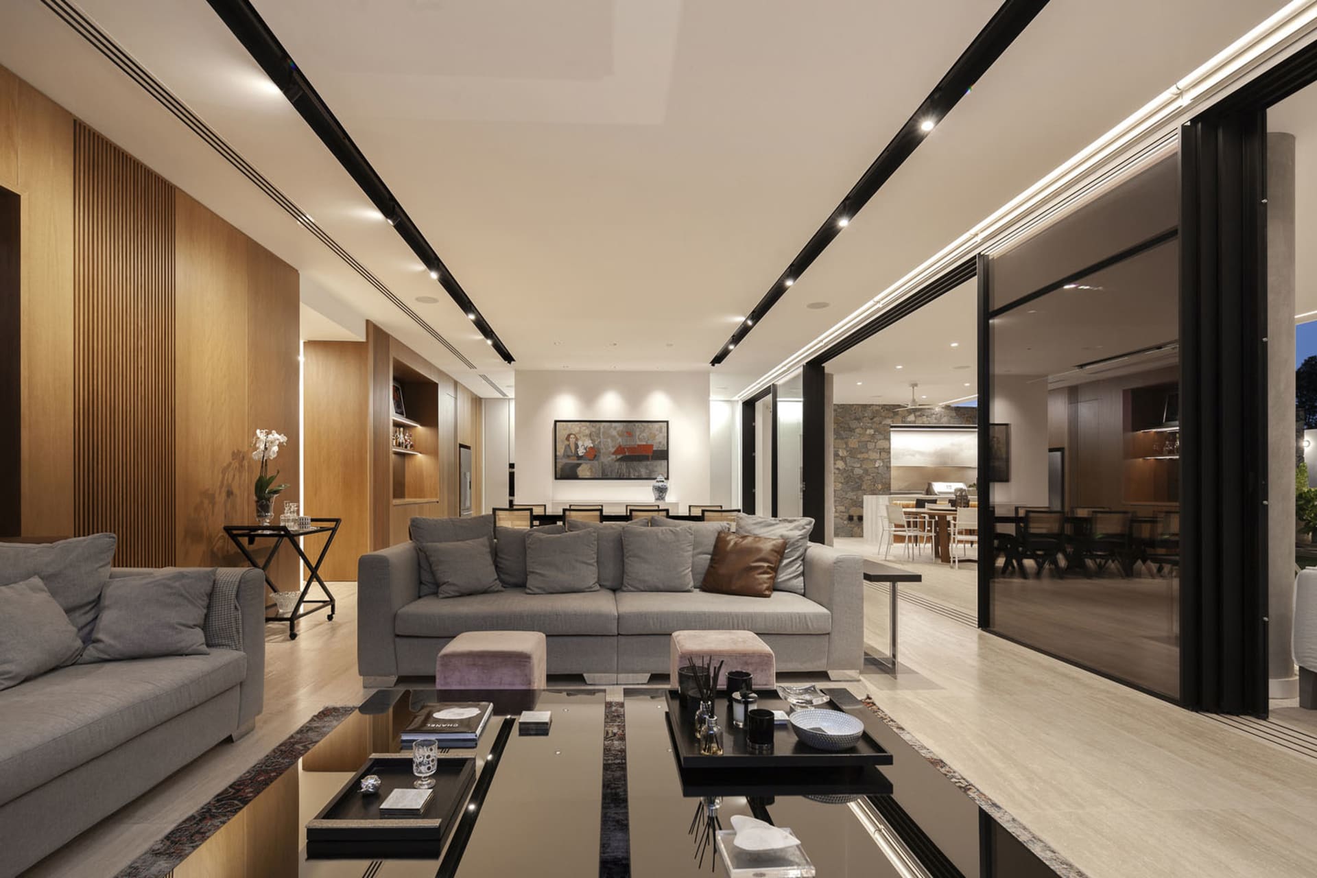 Modern living room interior with hardwood floors, large glass panels, and fabric seating.