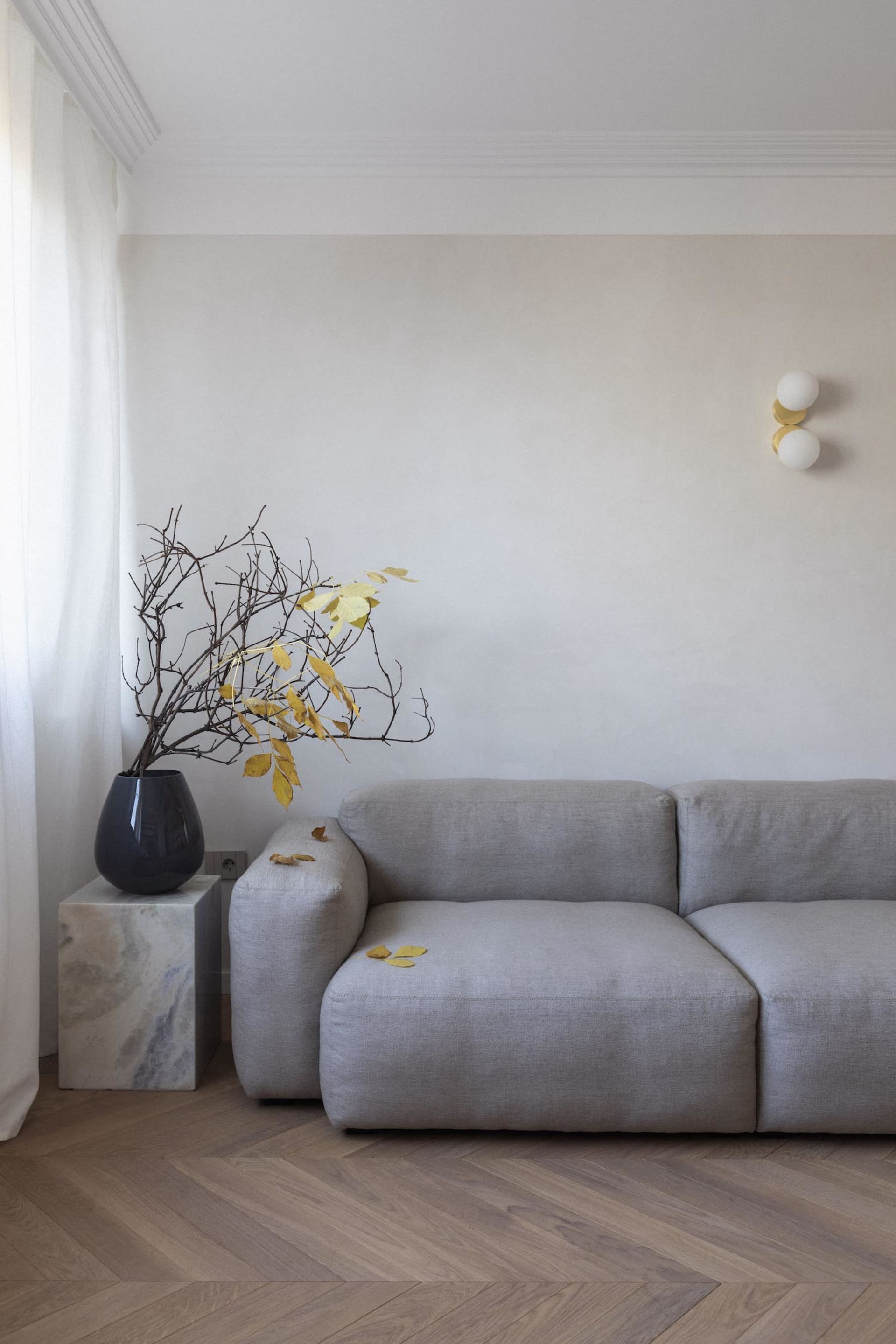 Modern living room featuring minimalistic furniture and a grey sofa.