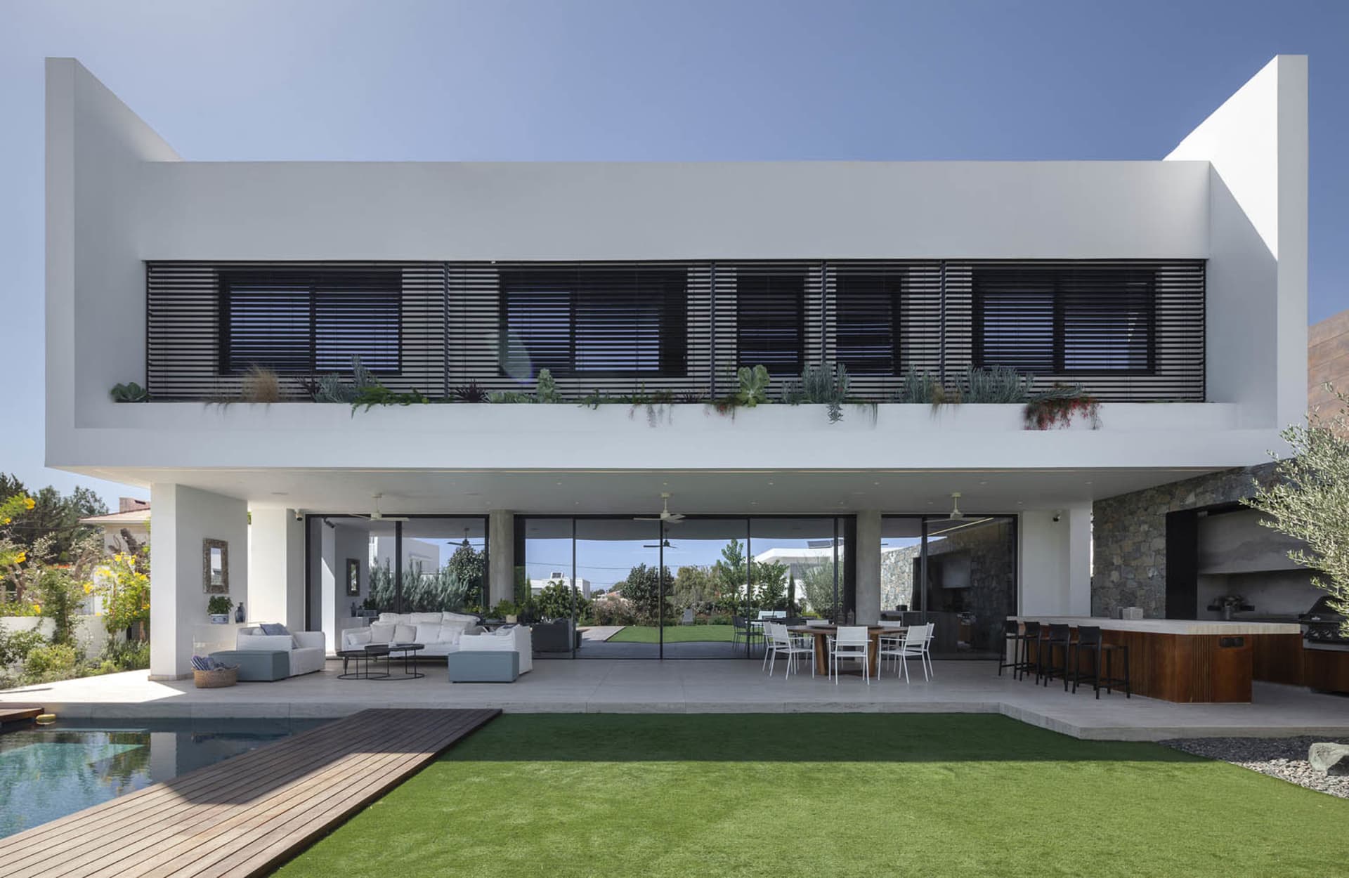 Modern residential space featuring a large patio, swimming pool, and outdoor dining area with a mix of concrete, glass, and w