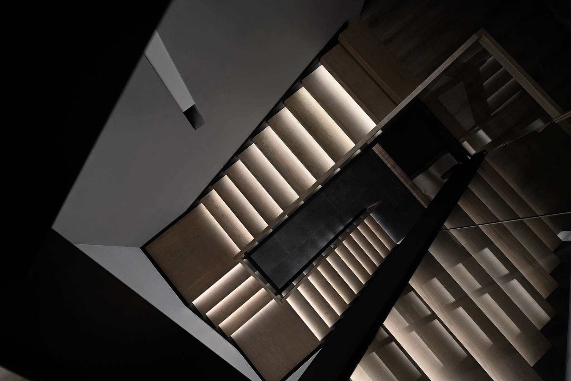 A modern staircase featuring wooden steps and railings, viewed from above.