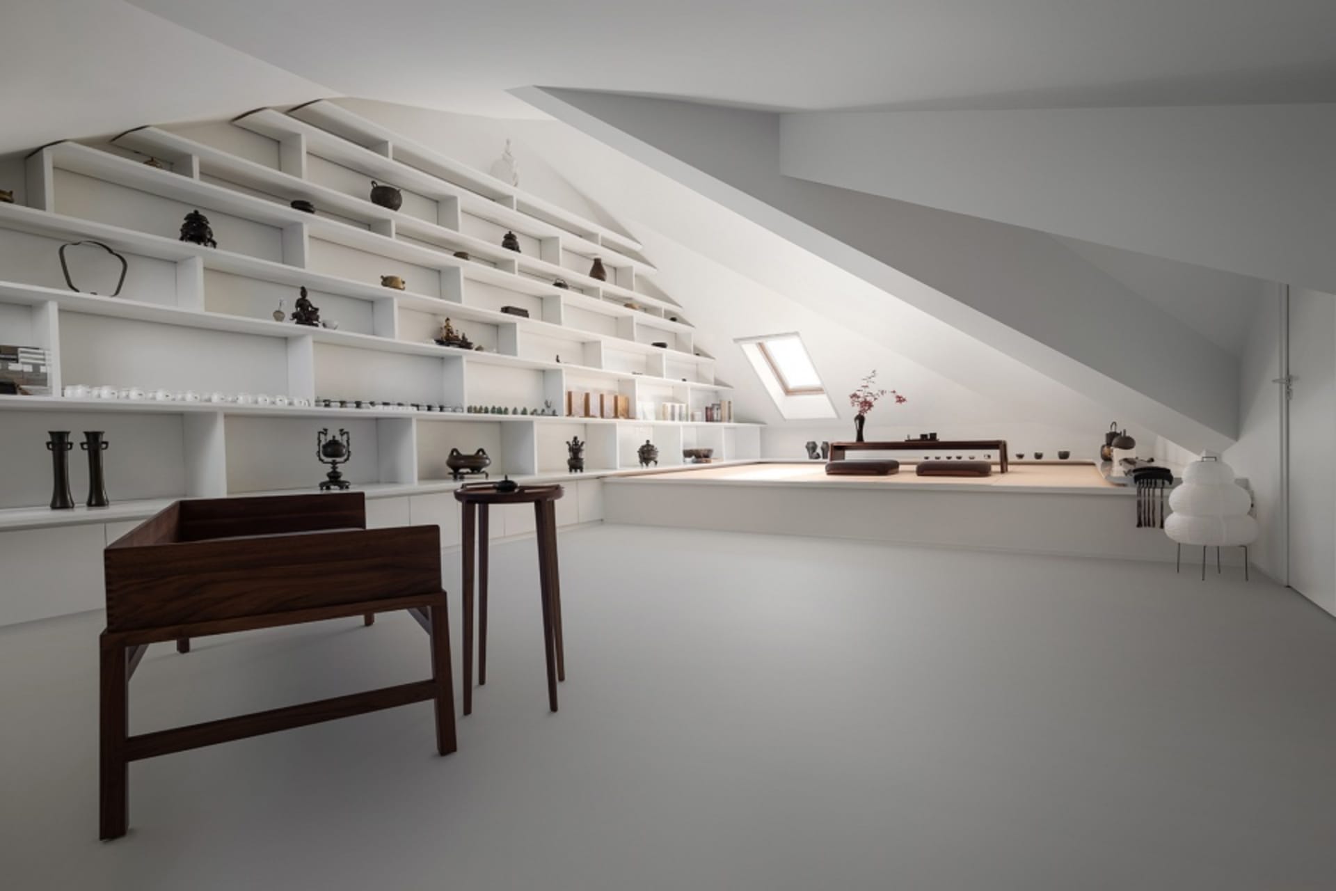 A minimalist living space with white walls, shelves, and furniture in white and dark wood.