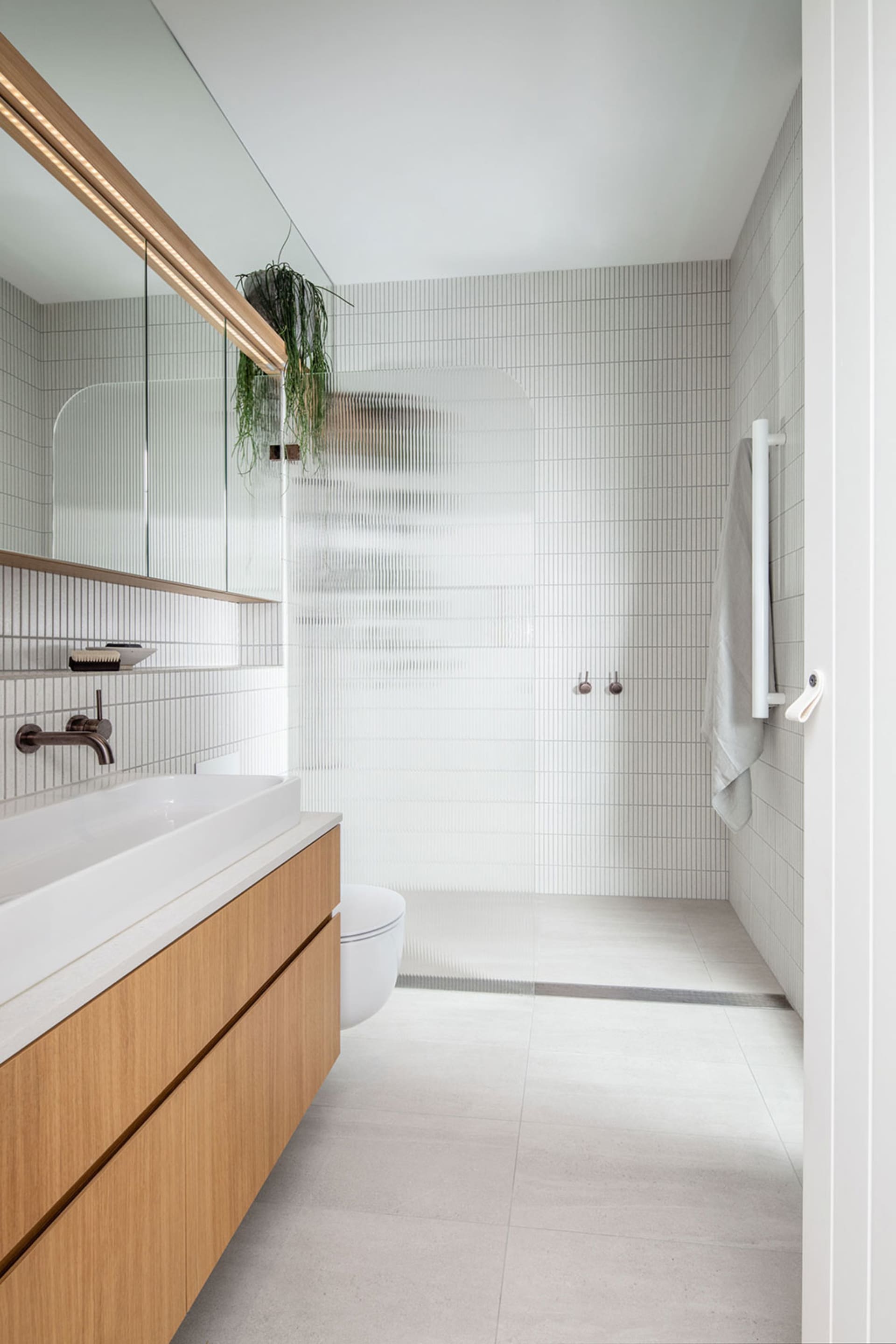 Modern bathroom with white textured tiles and wooden vanity