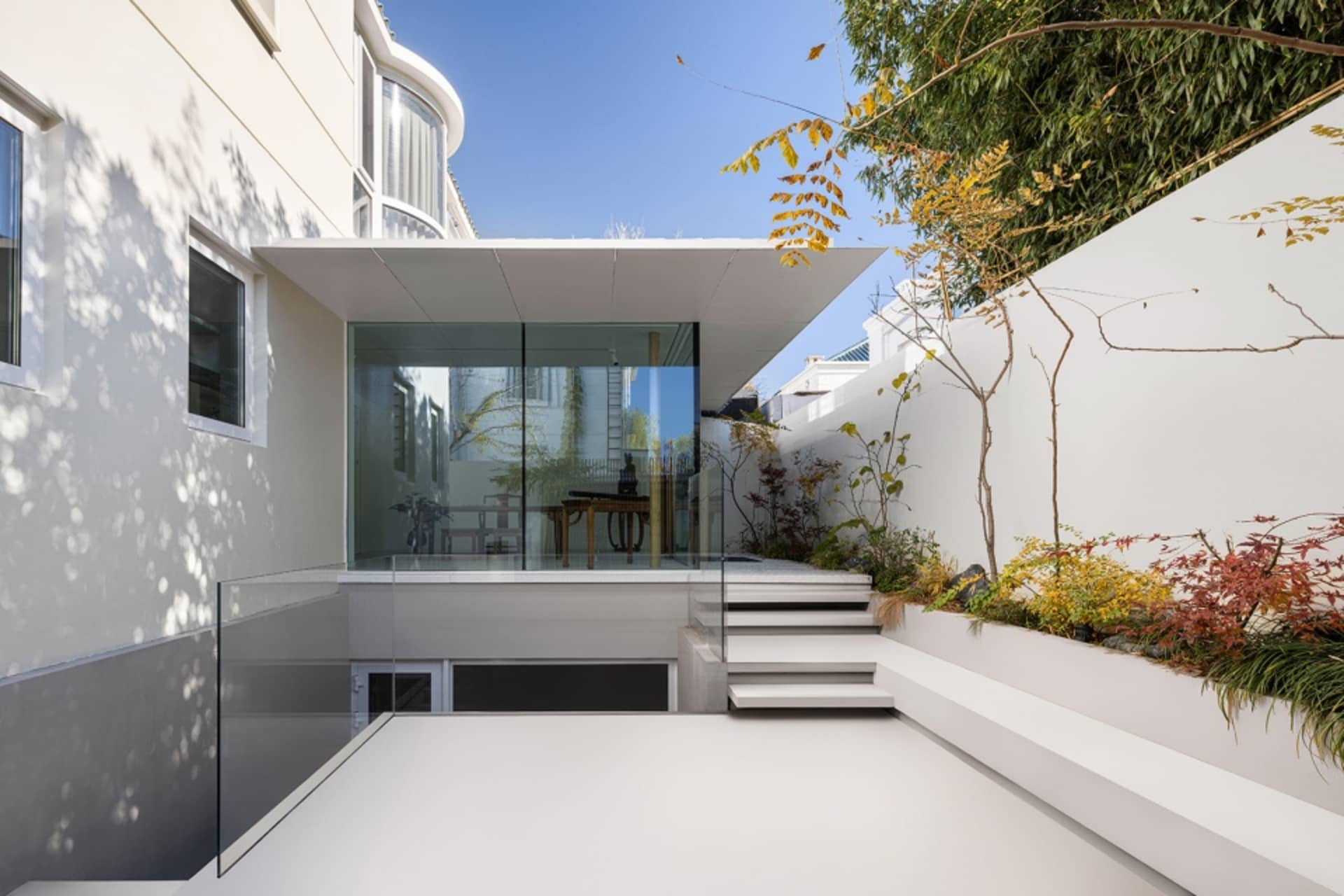 Modern, minimalist glass extension with white walls and outdoor space.