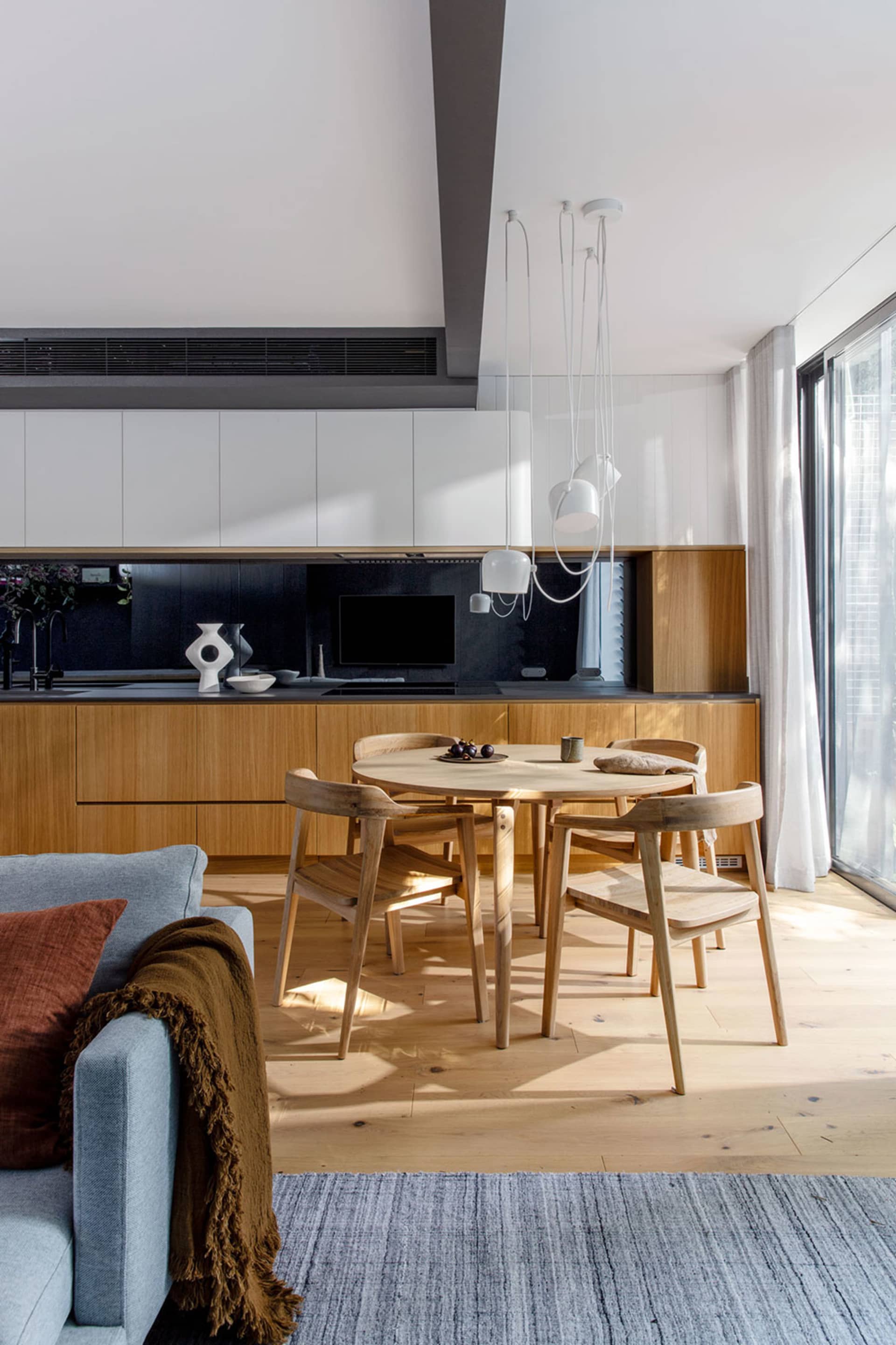 A modern residential kitchen with wood cabinets and a wooden dining table.