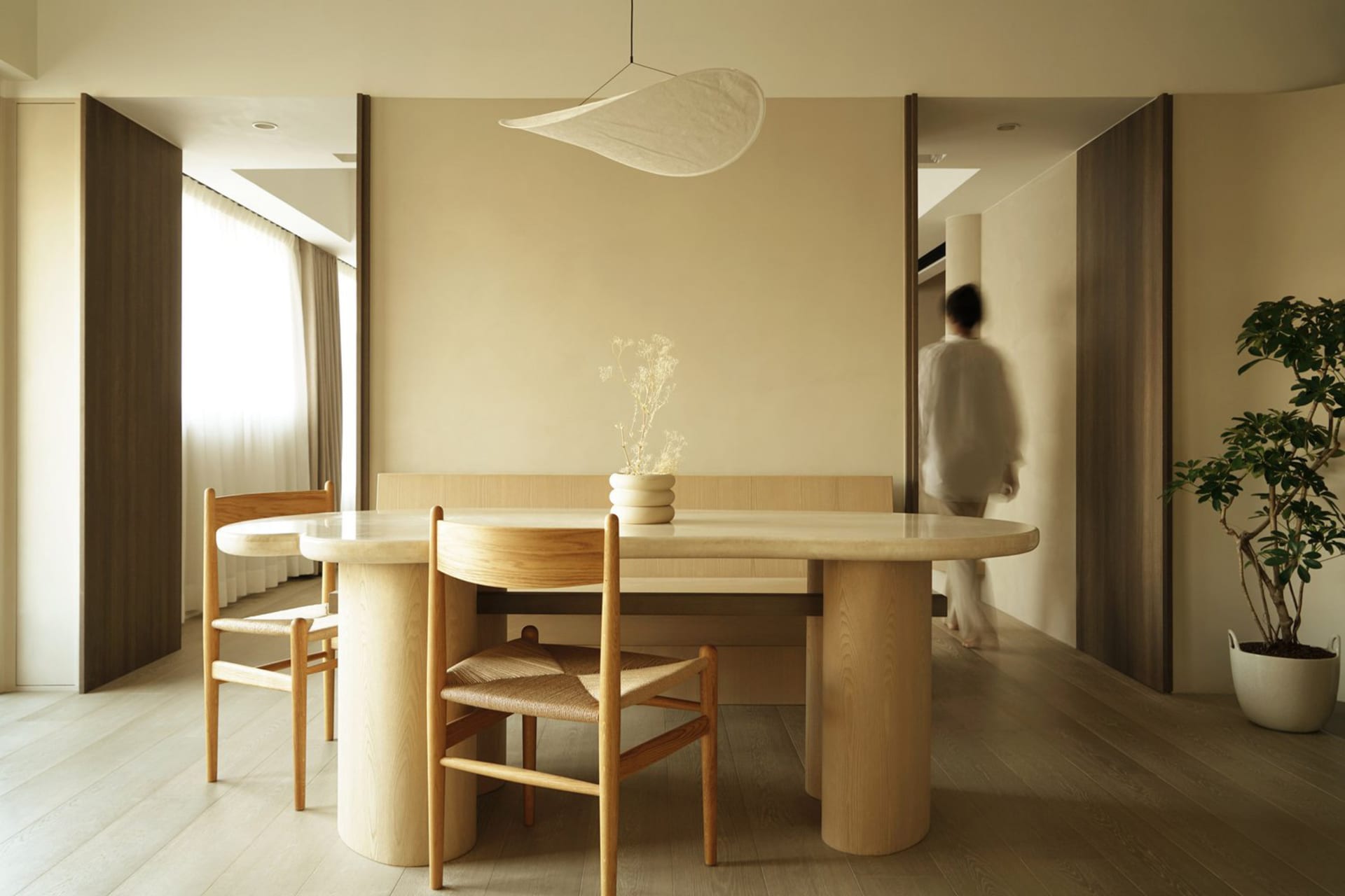 Minimalist dining room with wooden furniture and light-colored walls.
