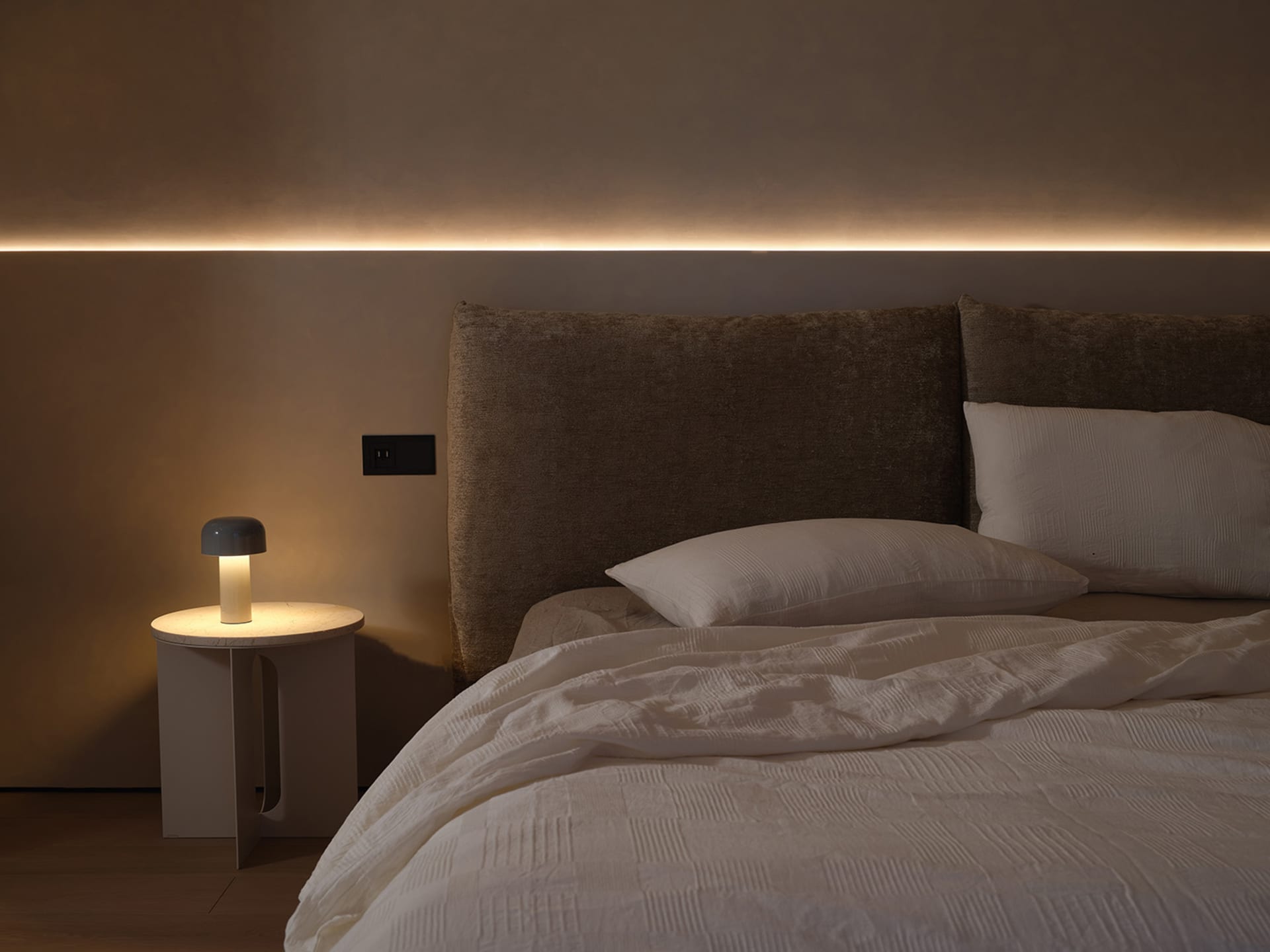 Minimalist bedroom with fabric headboard and linen bedding.