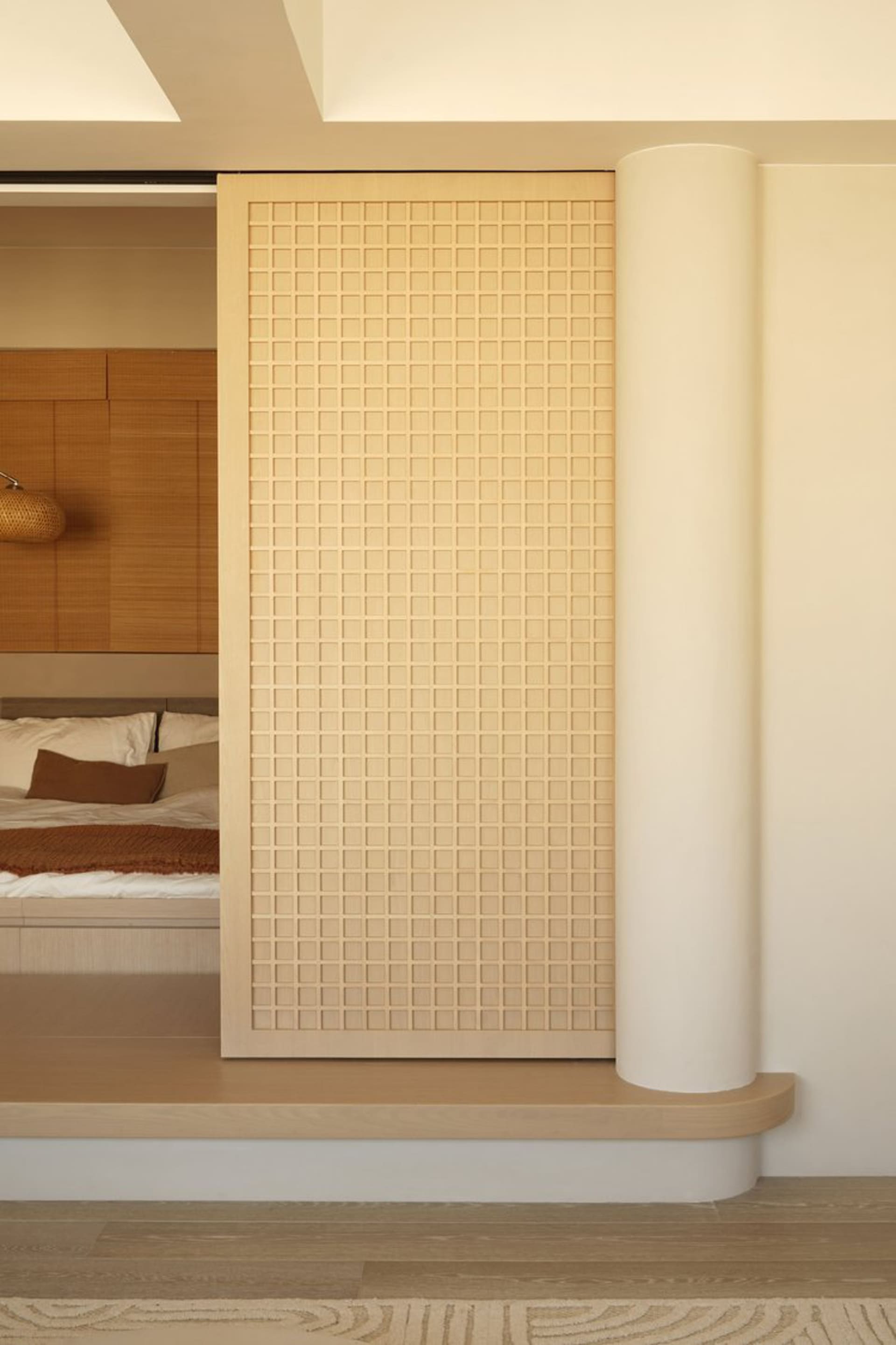Modern minimalist interior space with a light-colored tiled wall and wooden columns.