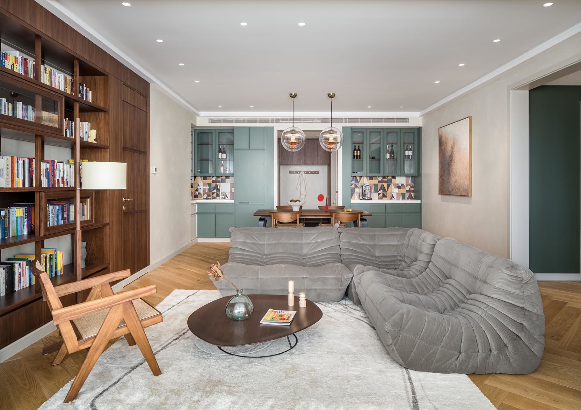 Modern interior design living room with a cozy gray sofa, wooden coffee table, and bookshelf.