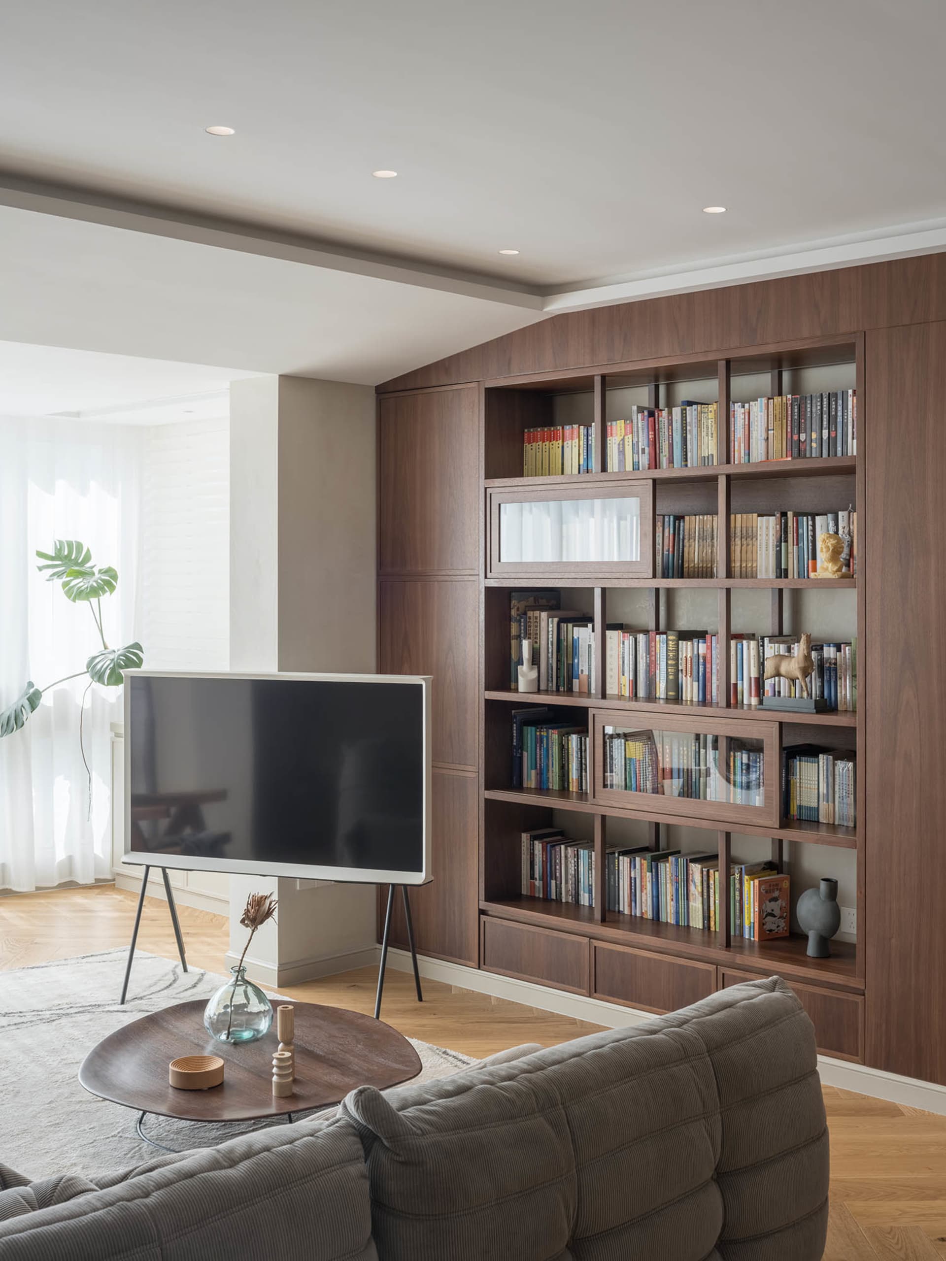 A modern living room featuring wooden shelves filled with books and decorative items.