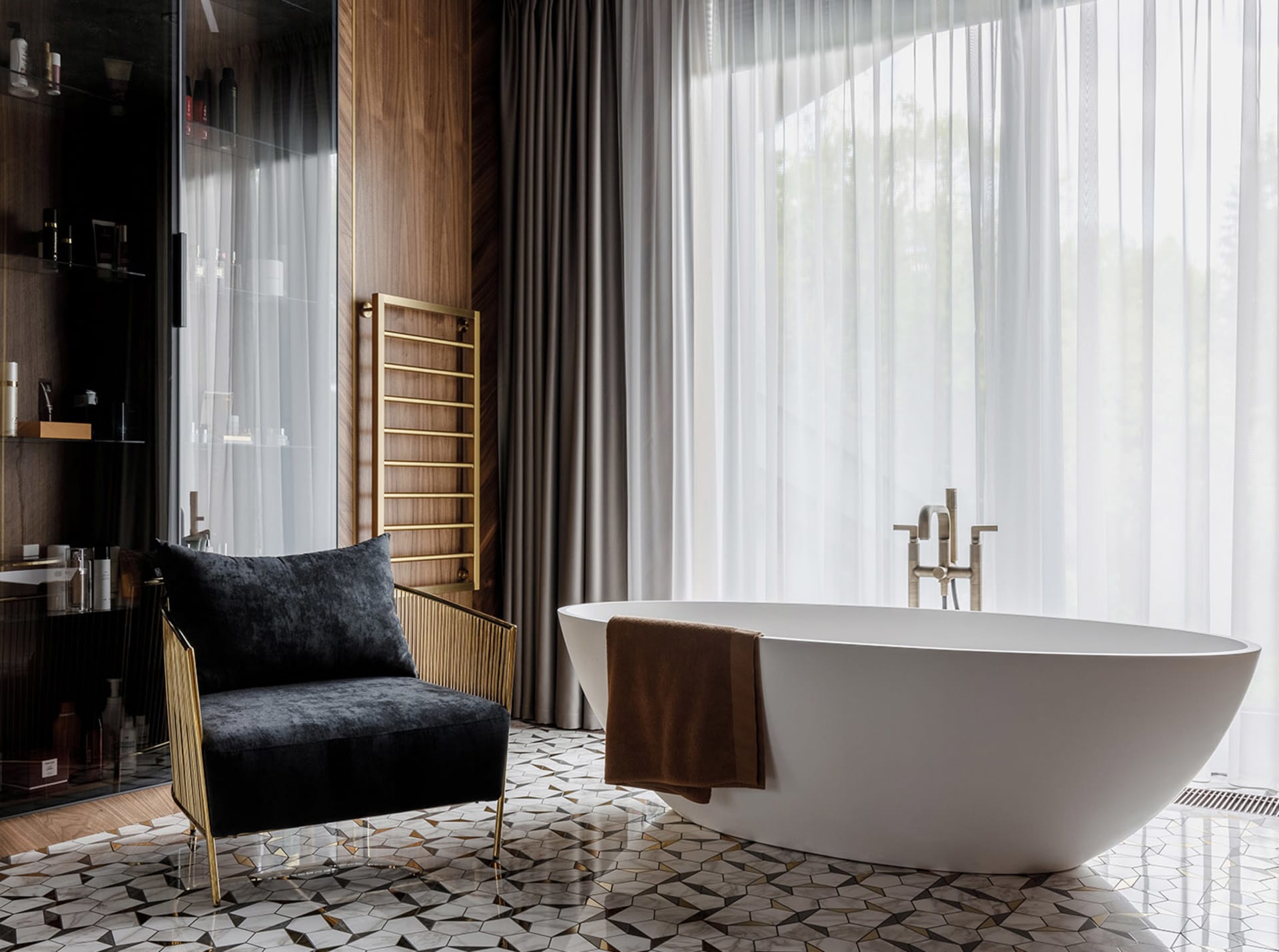 Modern bathroom with white marble floor, freestanding bathtub, and black armchair.