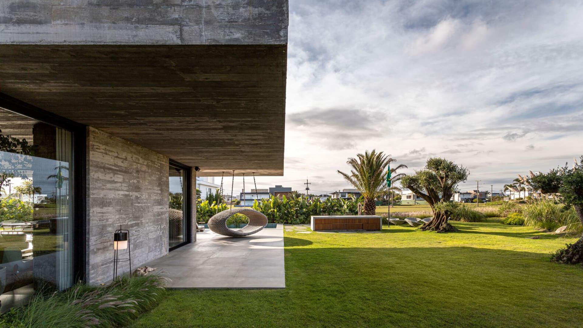 Modern house with concrete and glass exterior, featuring a garden view.