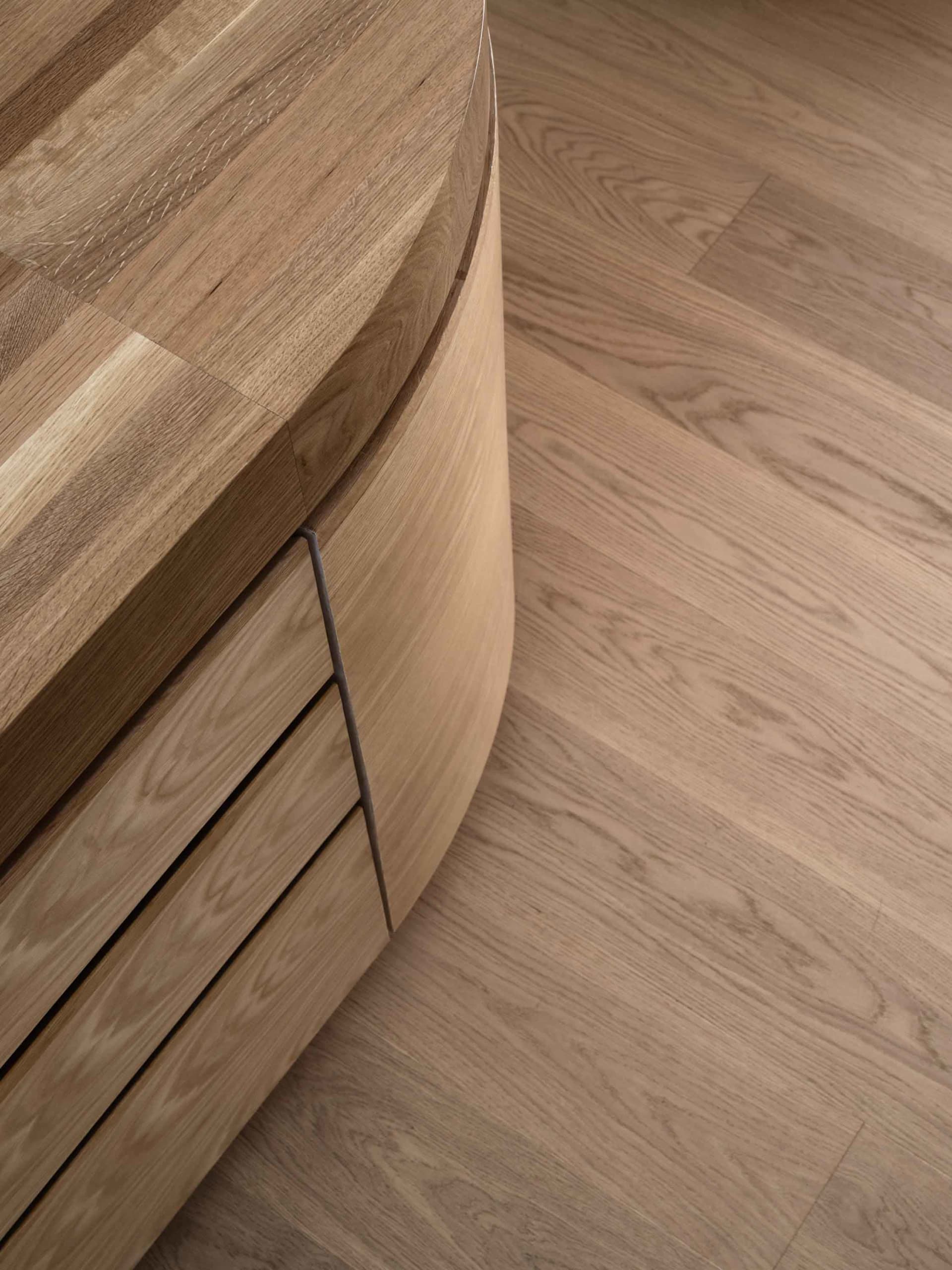 A modern interior design featuring a curved wooden case with a textured surface and minimalistic styling.