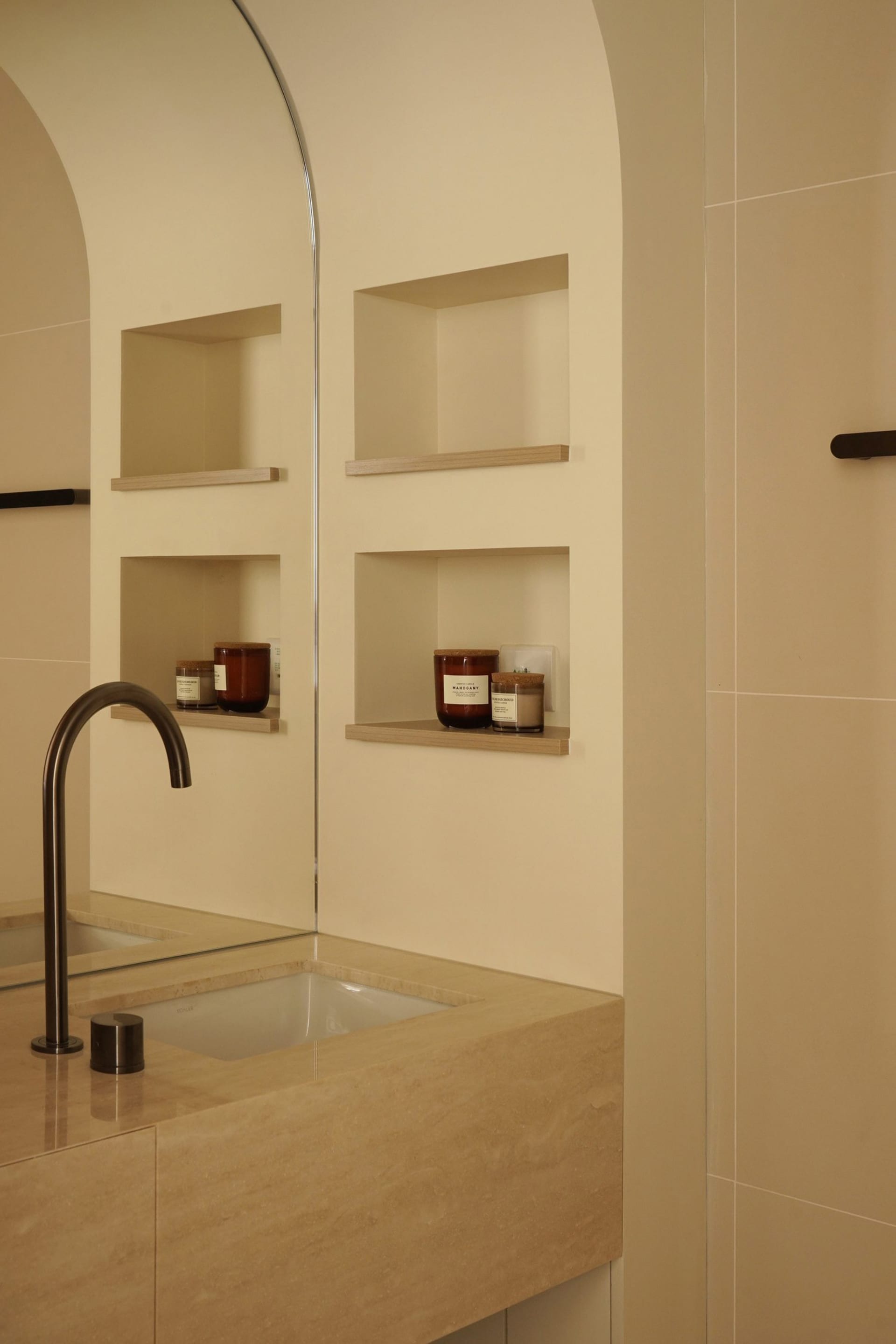 Modern bathroom interior with a marble countertop, built-in shelves, and a sleek faucet.
