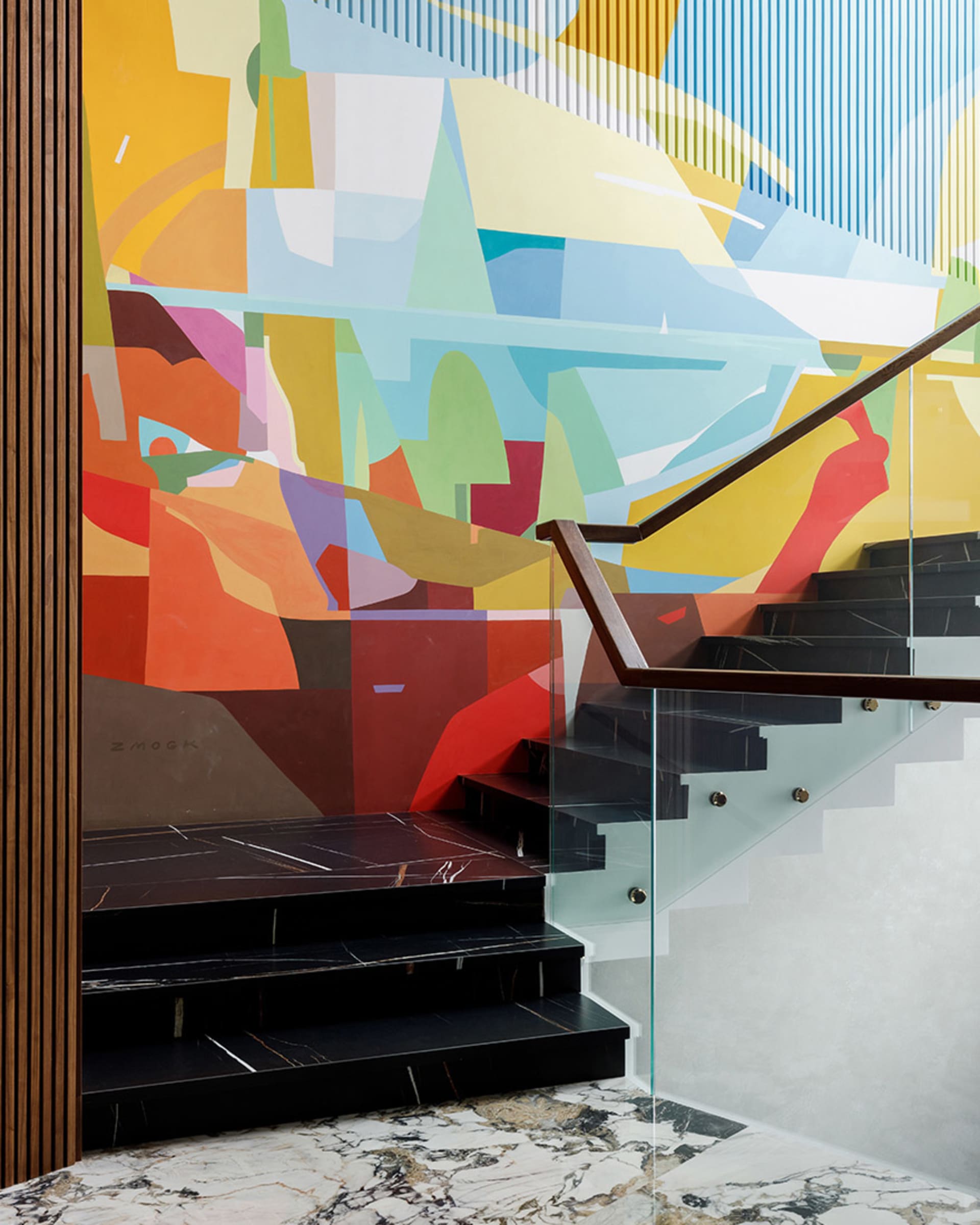 A modern staircase featuring artistic mural of geometric shapes and lines on a wall with glass and metal railings and marble