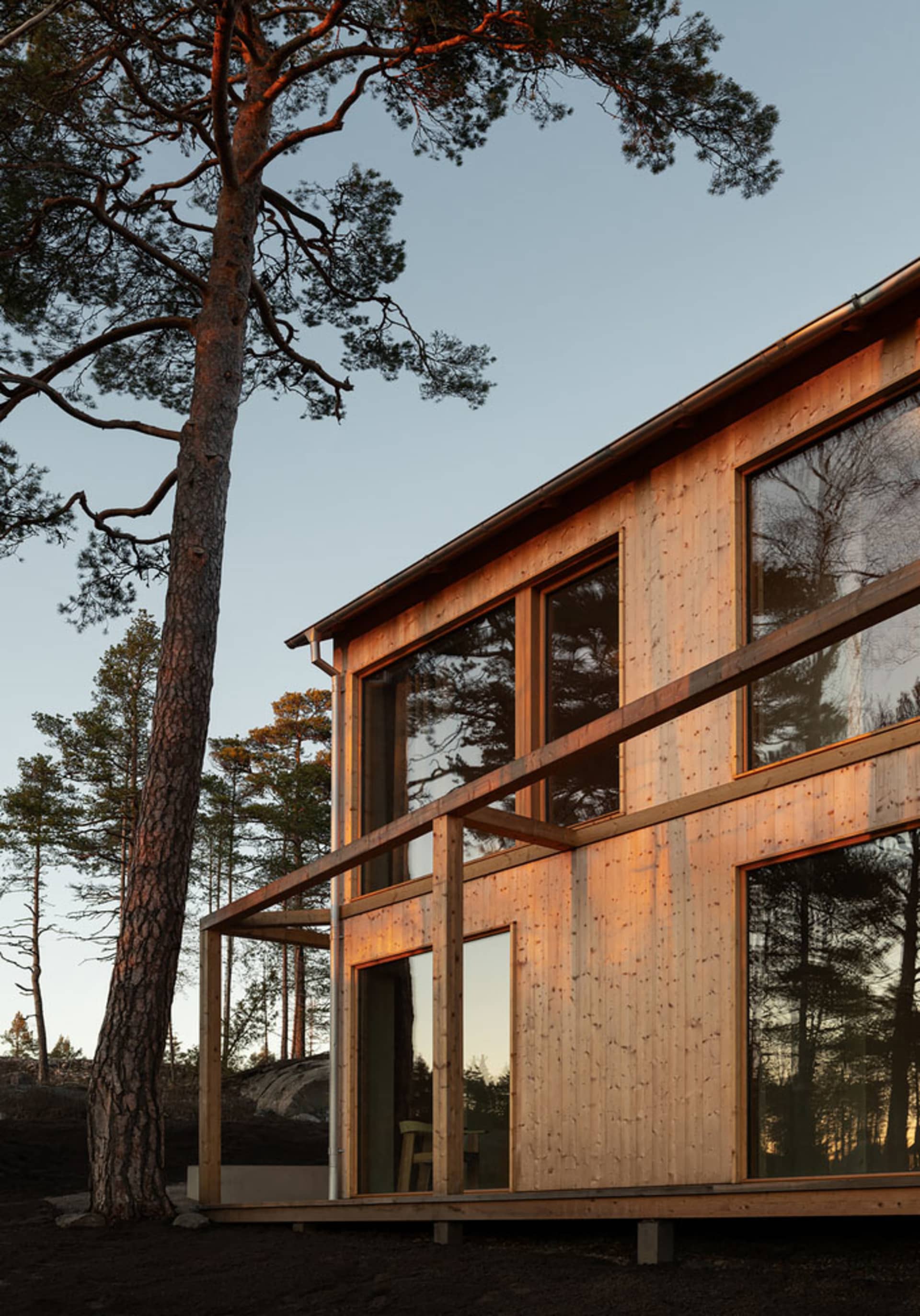 Modern wooden residence with large windows at sunset.