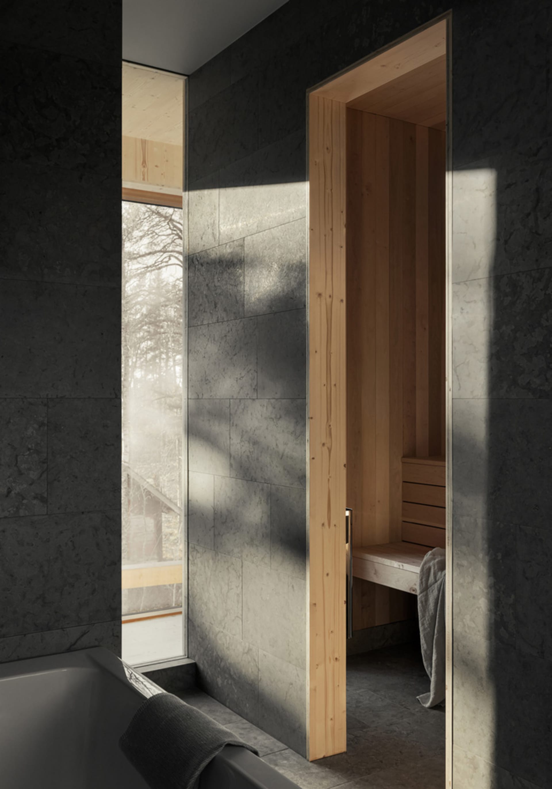 Modern bathroom with gray marble walls and a sauna in the background.