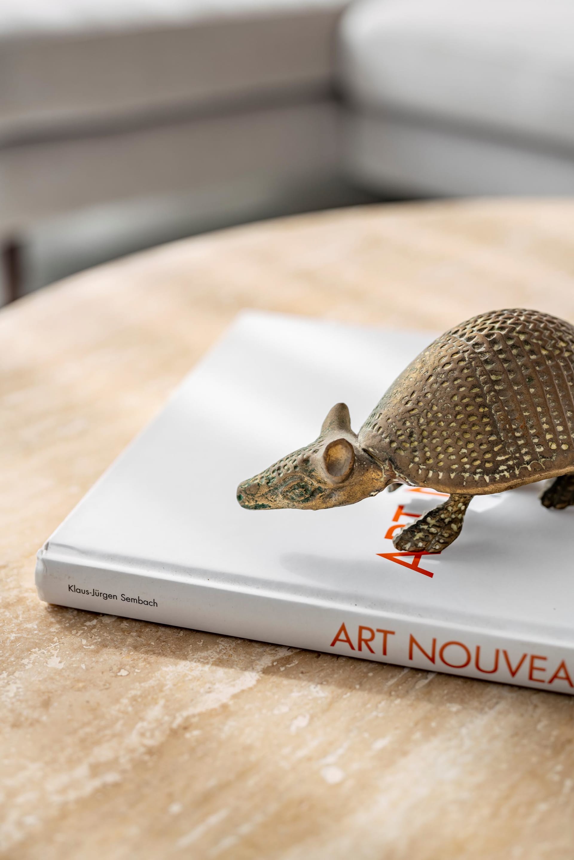 一件金屬犰狳雕塑靜置於一本書上，書名為「Art Nouveau」