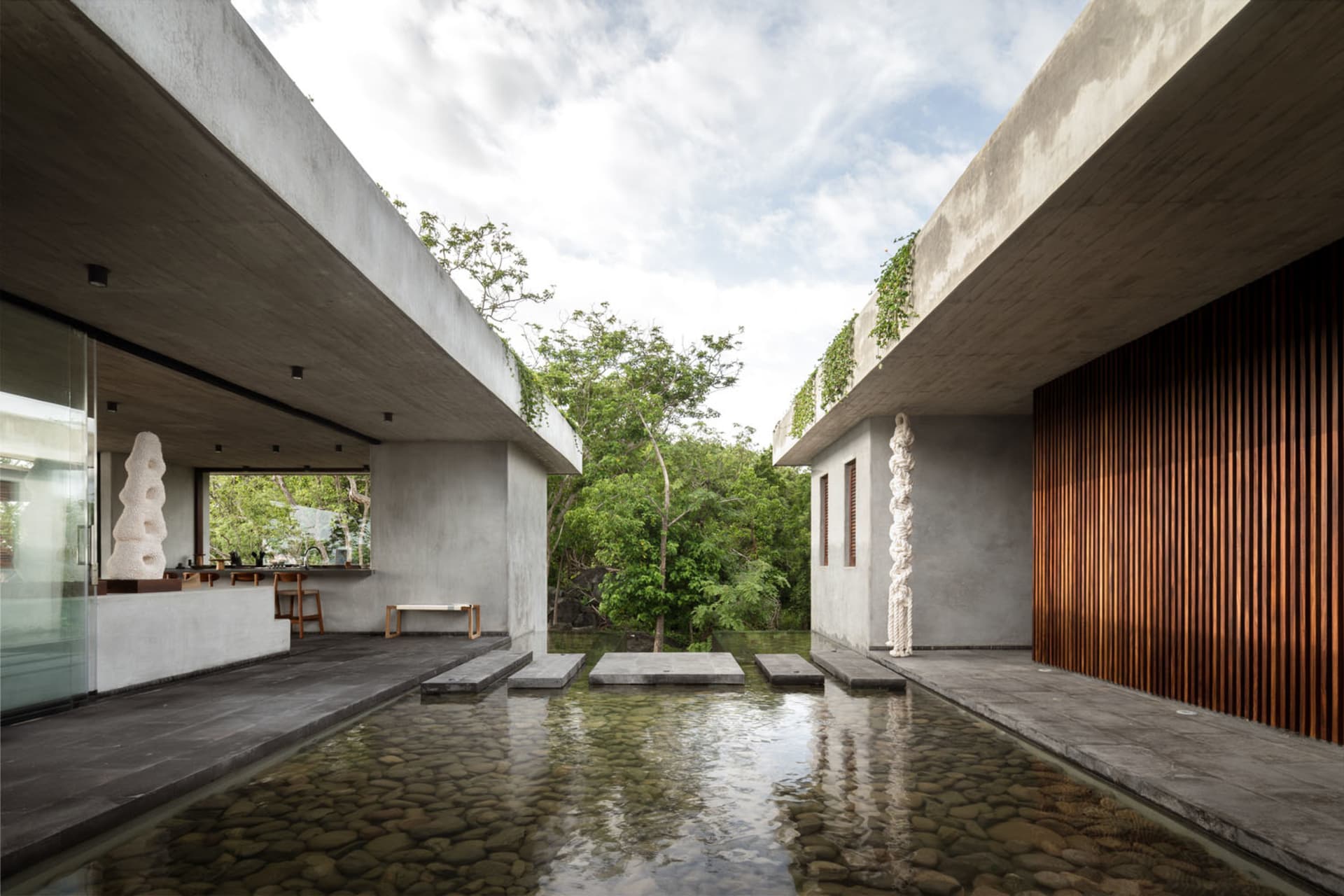 Industrial-style outdoor living space featuring concrete elements and a tranquil water feature.