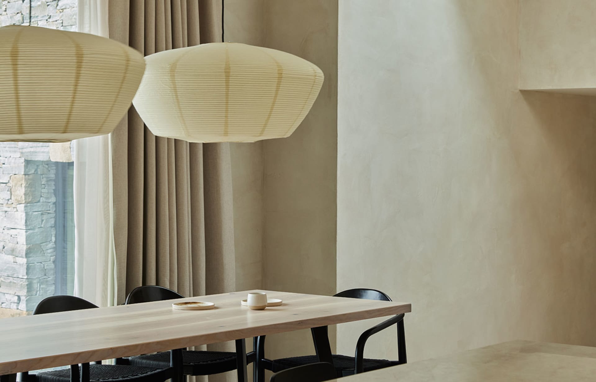 A minimalist dining room featuring wooden furniture and modern lighting.
