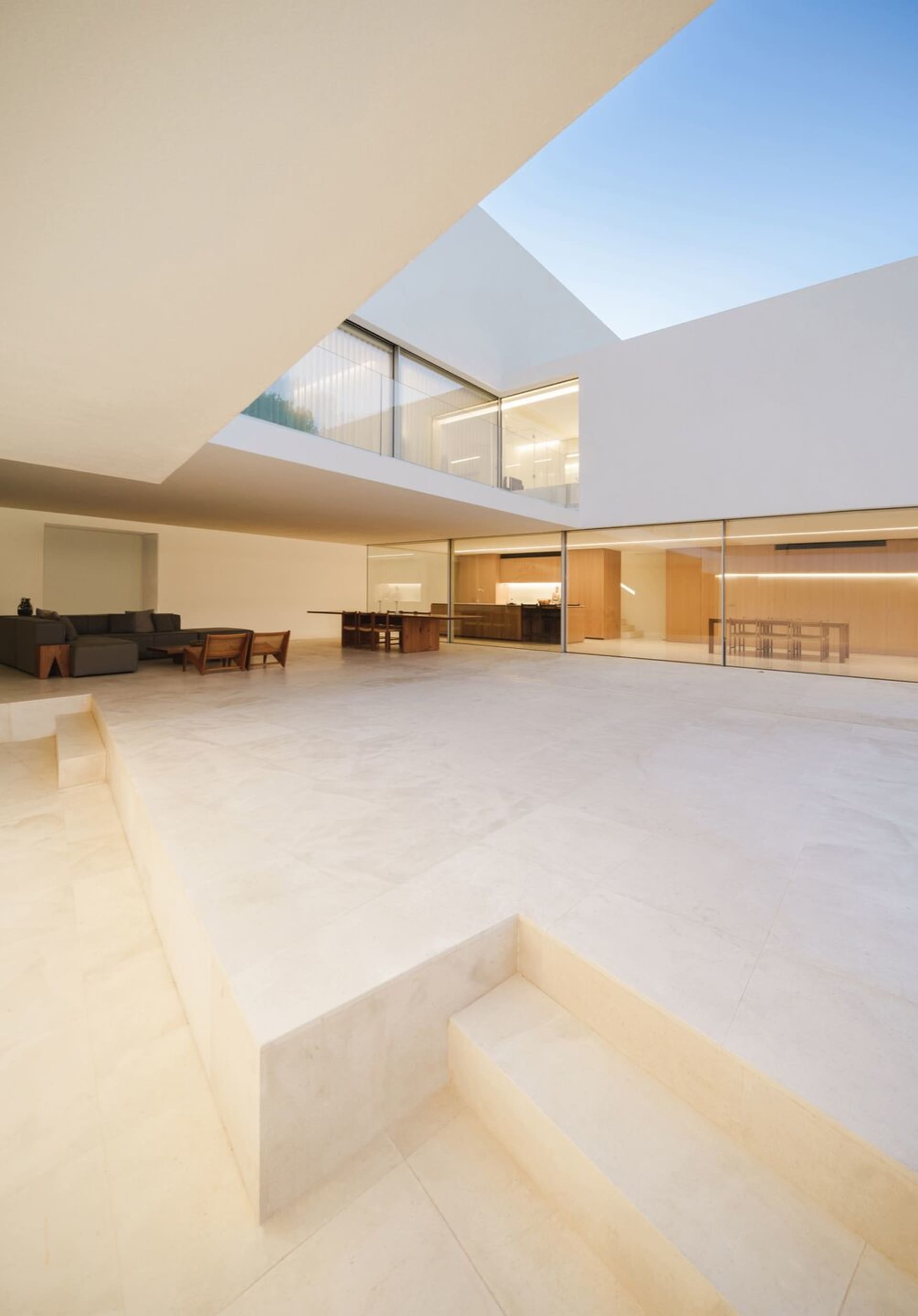 Modern interior with white tiled floors, large windows, and a mix of furniture and lighting.