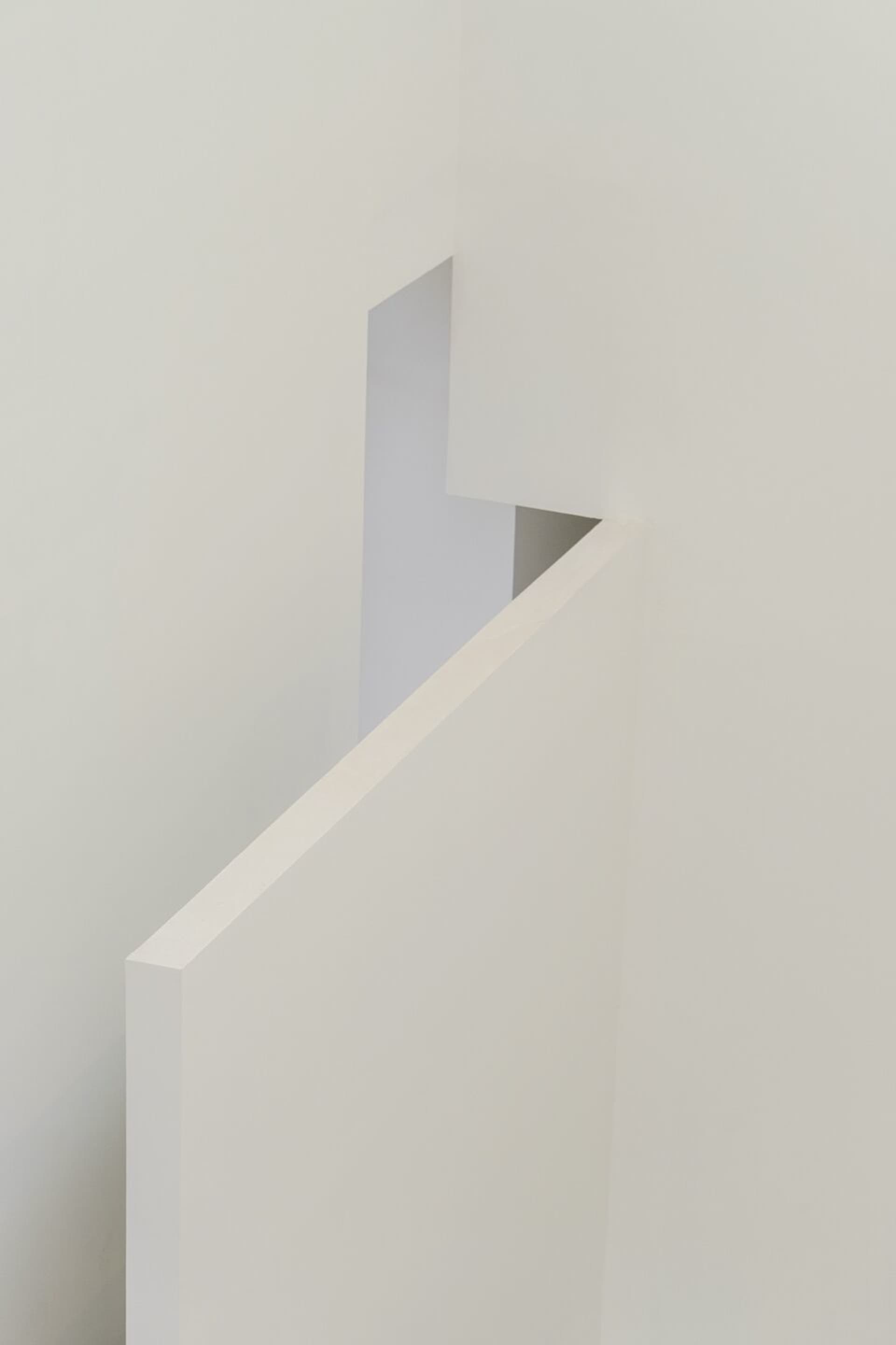 A minimalist hallway with white walls and a white staircase.