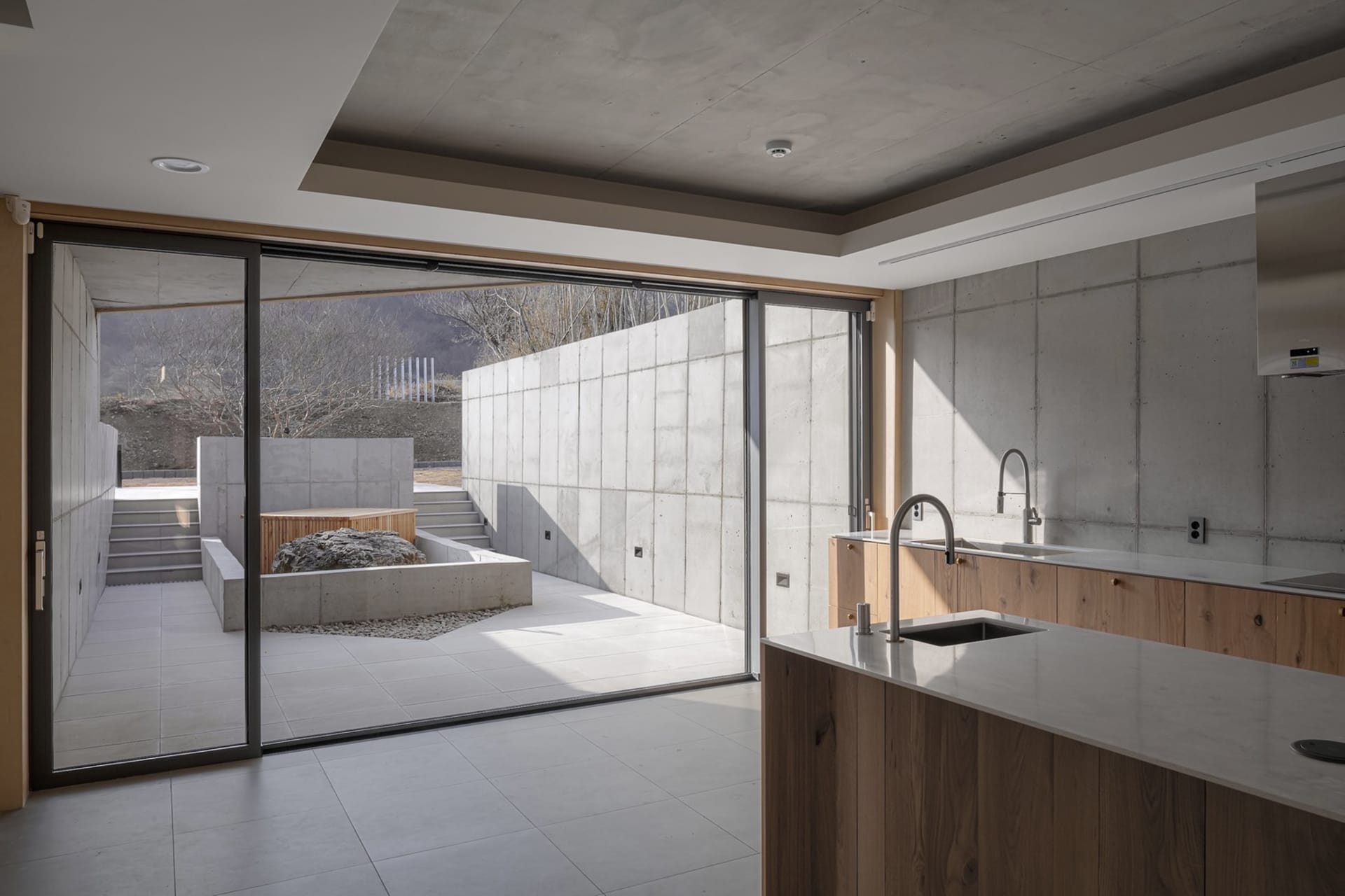 A modern kitchen with a minimalist design featuring concrete walls and flooring.