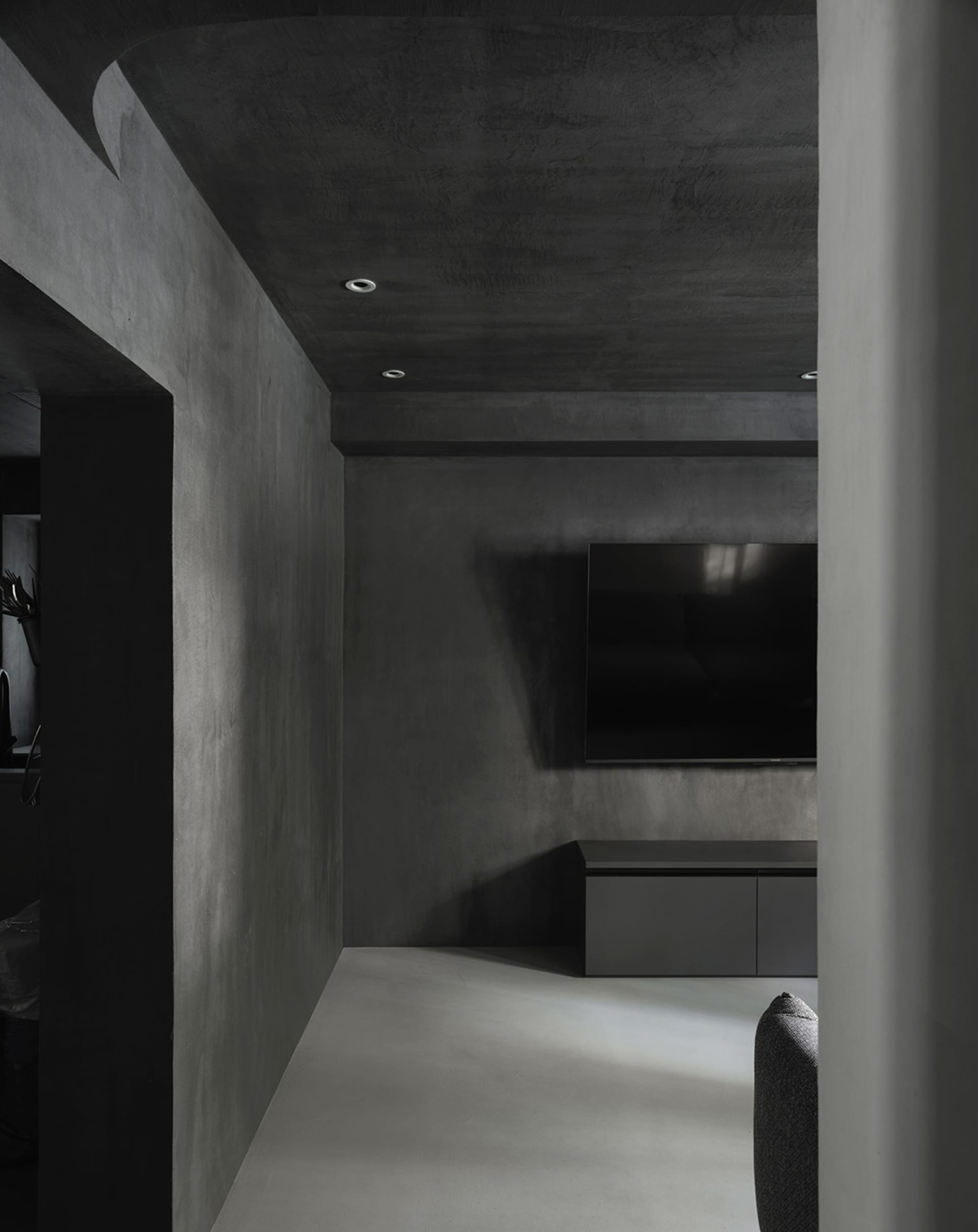 A modern living room featuring minimalist concrete walls and furniture.