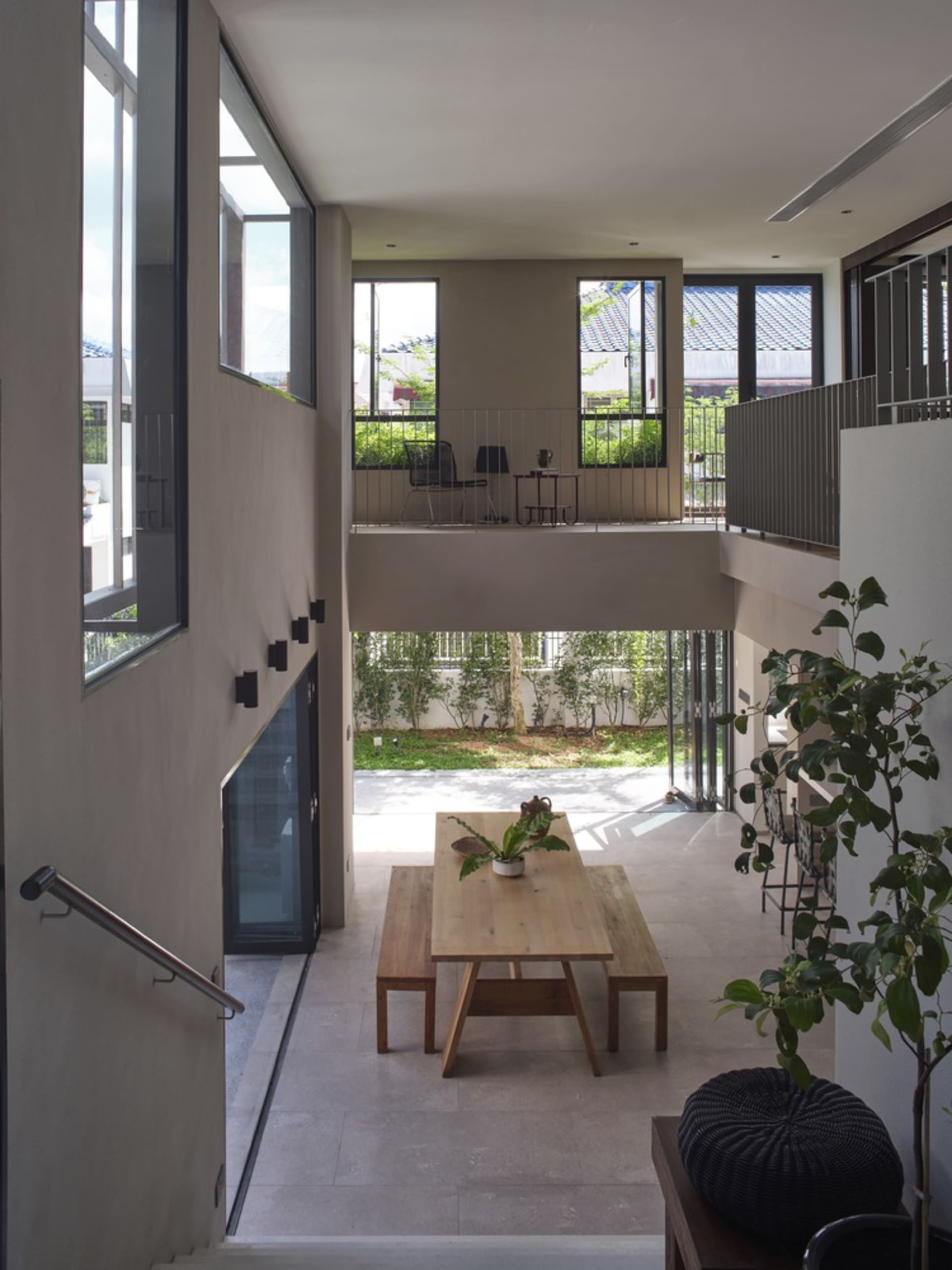 A modern living room with wooden table, concrete walls, and glass windows.