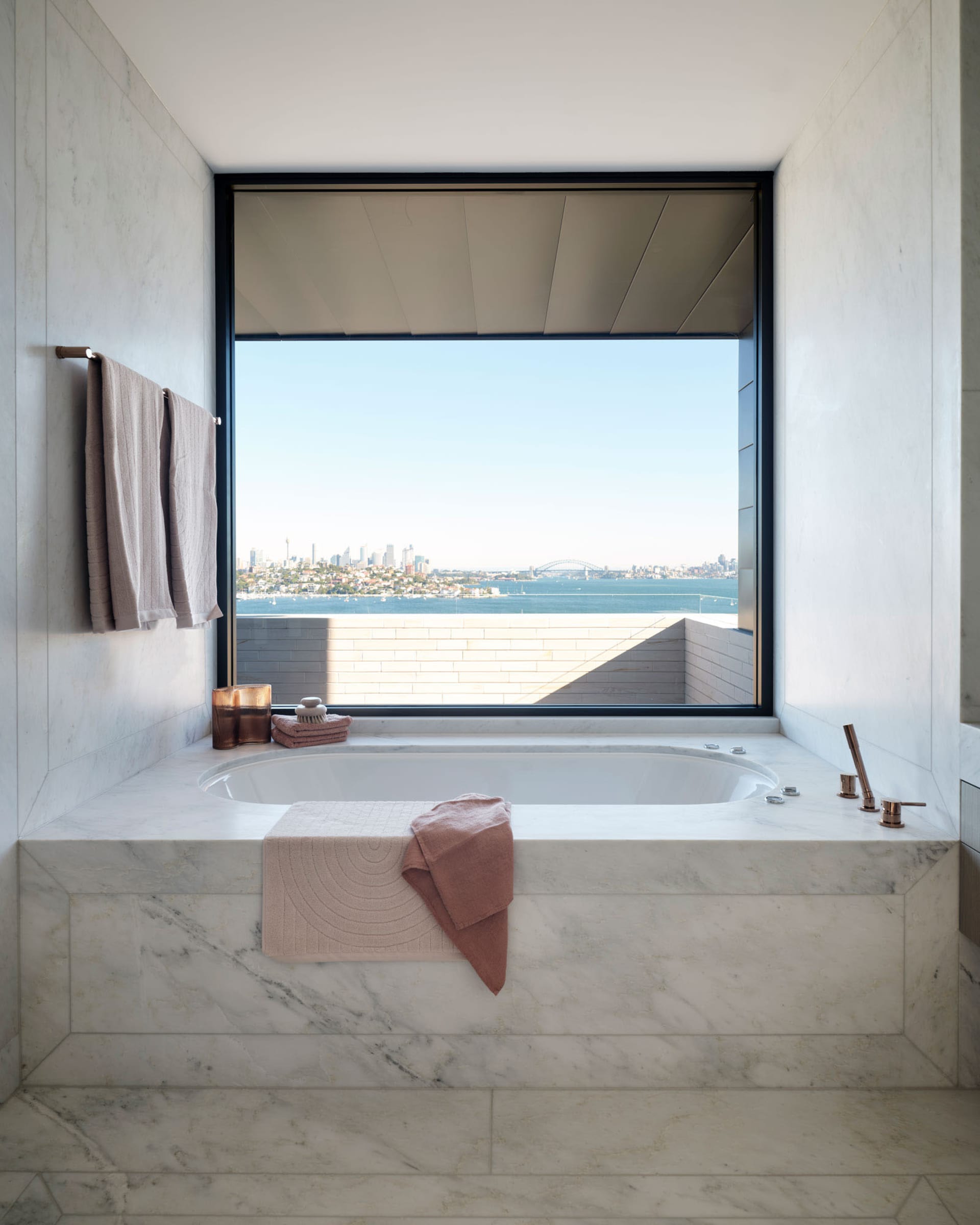 Modern minimalist bathroom with marble finish and large window overlooking the ocean.