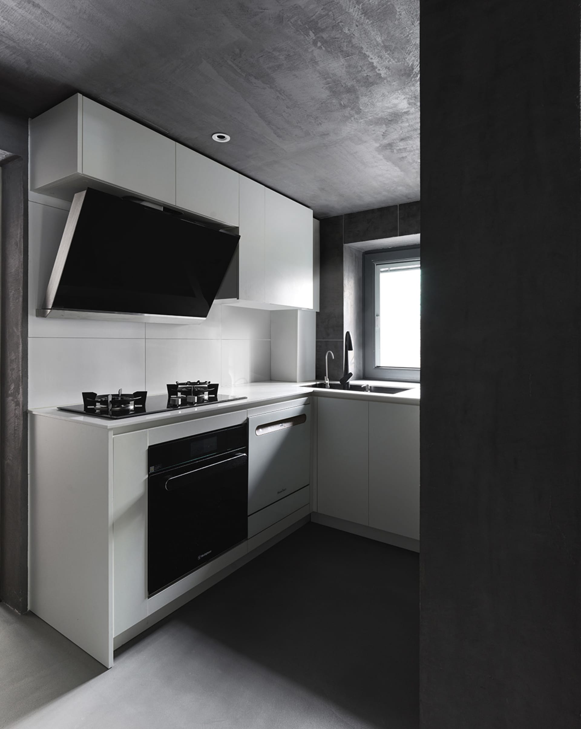 A modern kitchen featuring a minimalist design with white cabinets and concrete countertops.