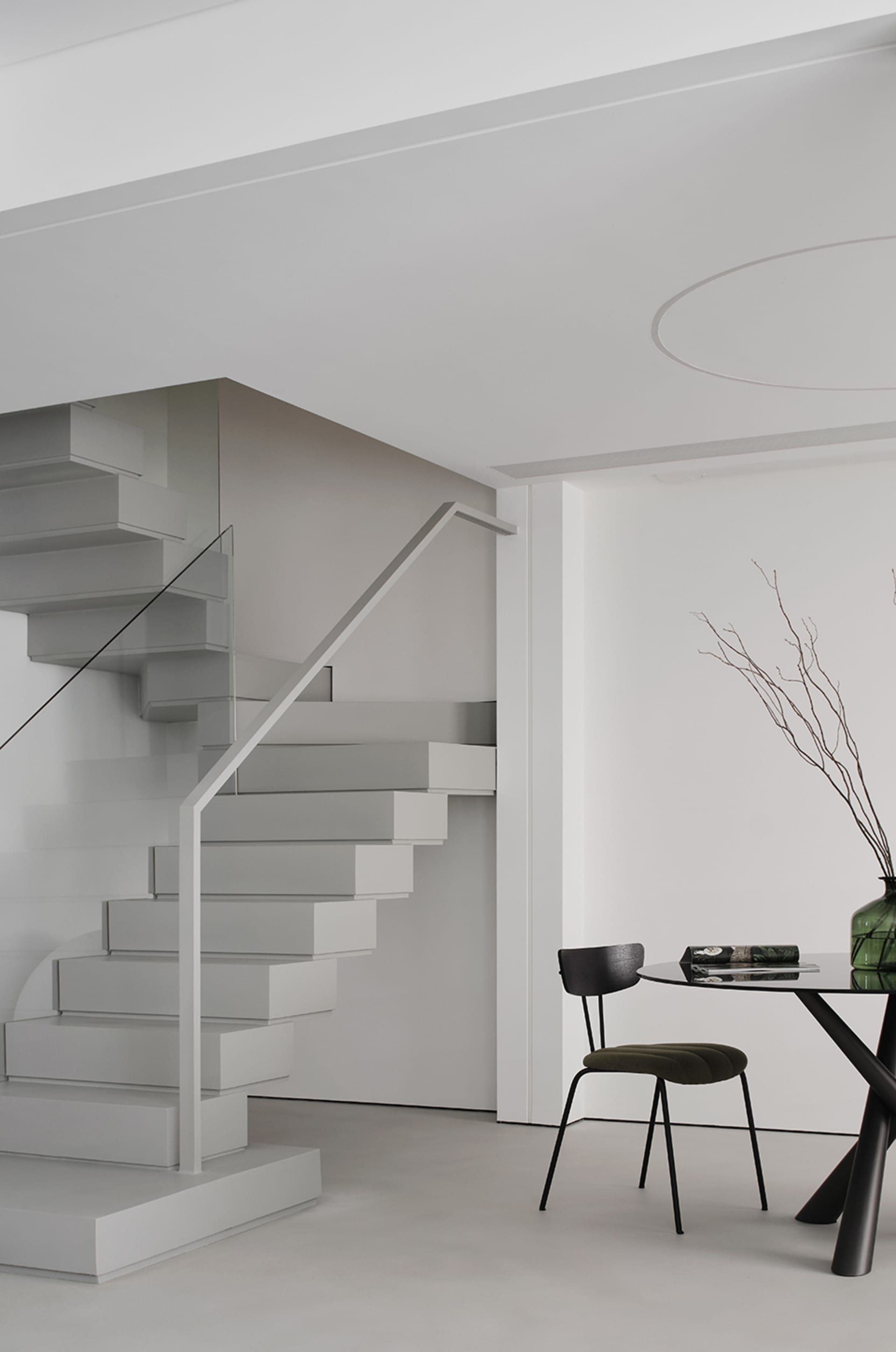 A minimalist interior space featuring a modern staircase with glass and metal elements.