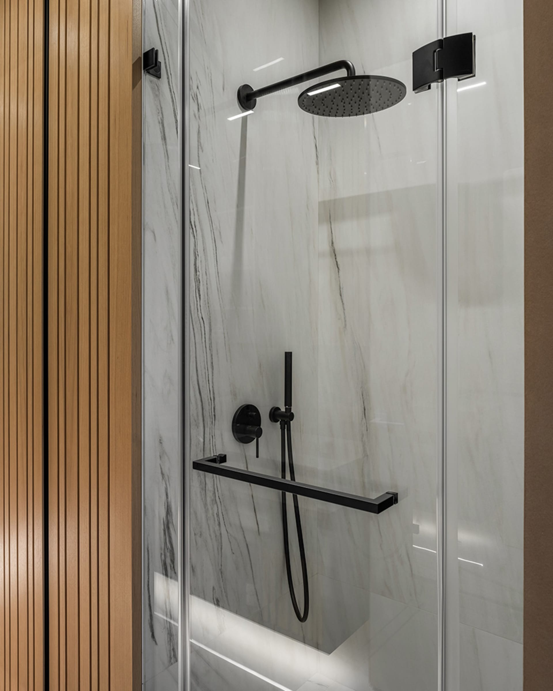 Modern bathroom shower with marble tiles and black steel fixtures