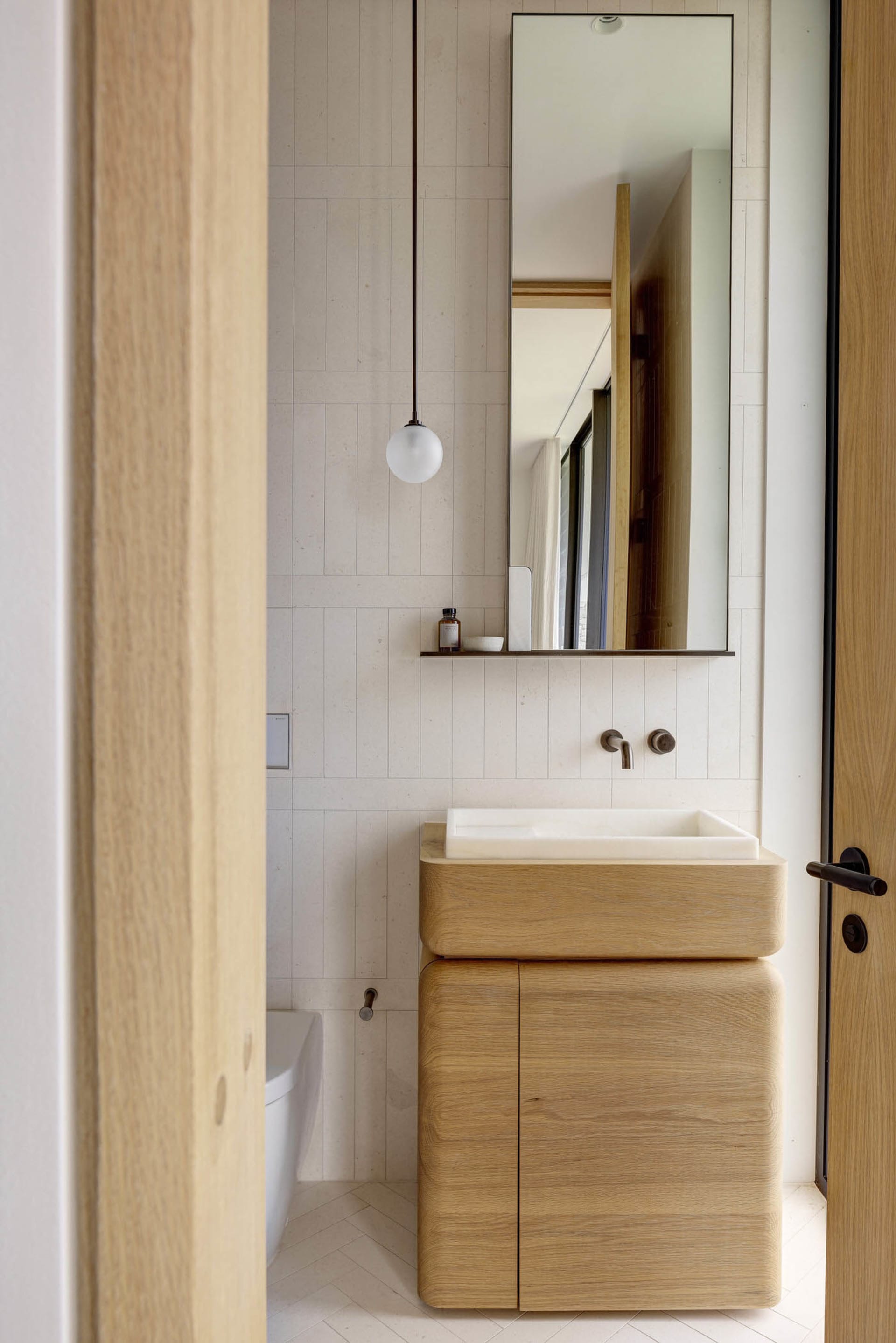 Modern minimalist bathroom with a wooden sink and tiled walls and floor.