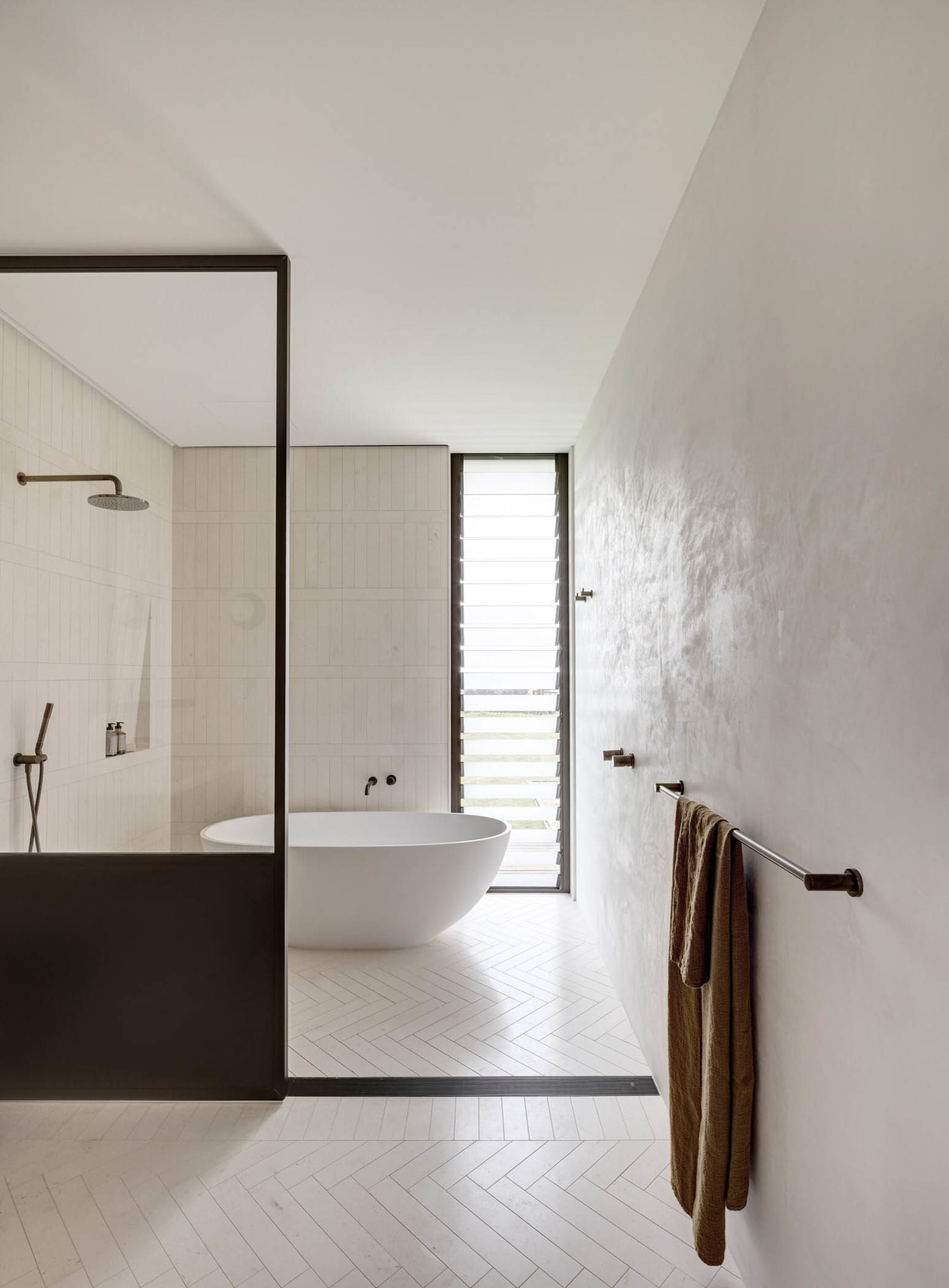 Modern bathroom featuring a white tiled floor and a white freestanding bathtub.