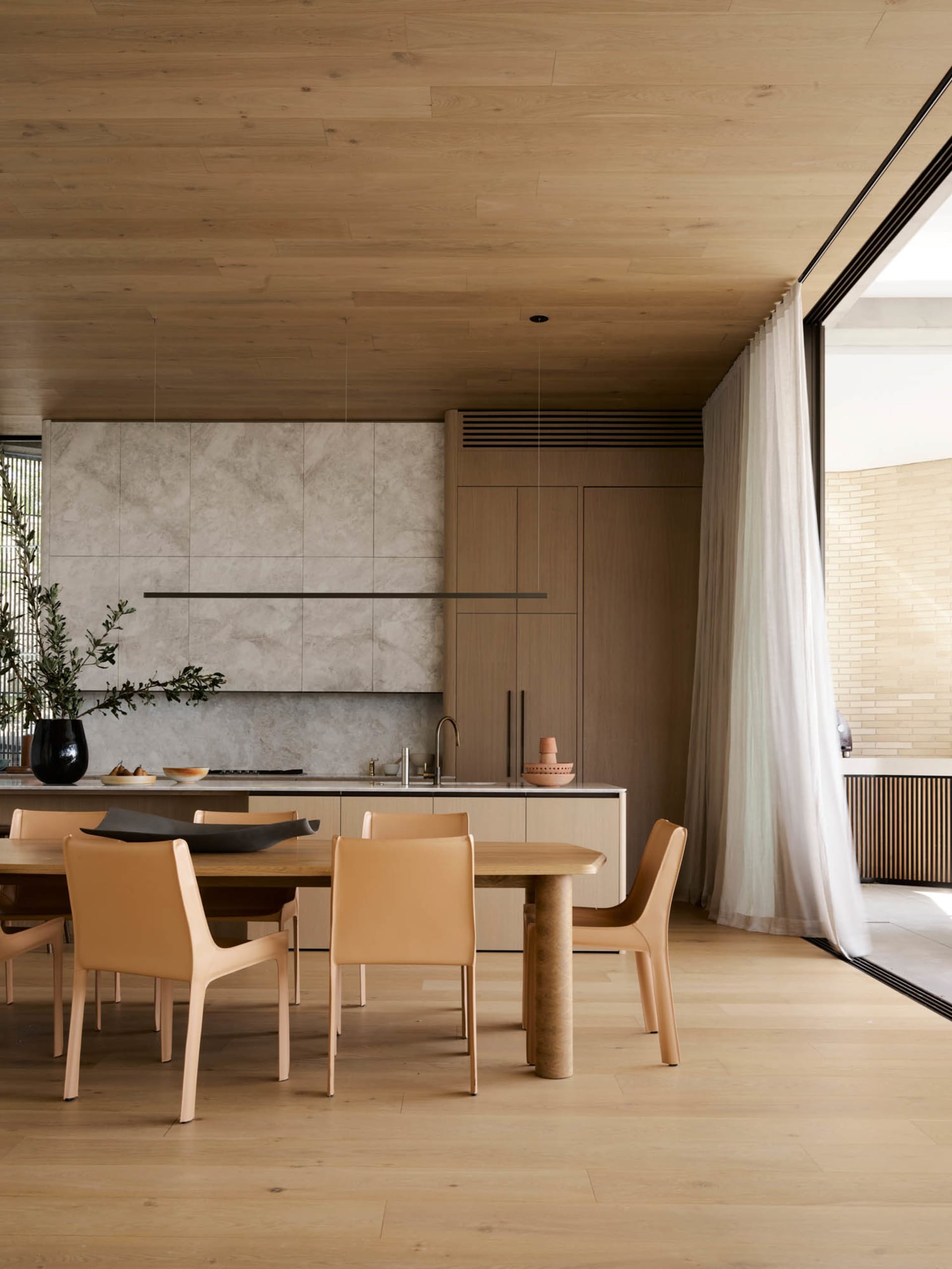 A photograph of a modern residential dining space featuring wood and marble elements.