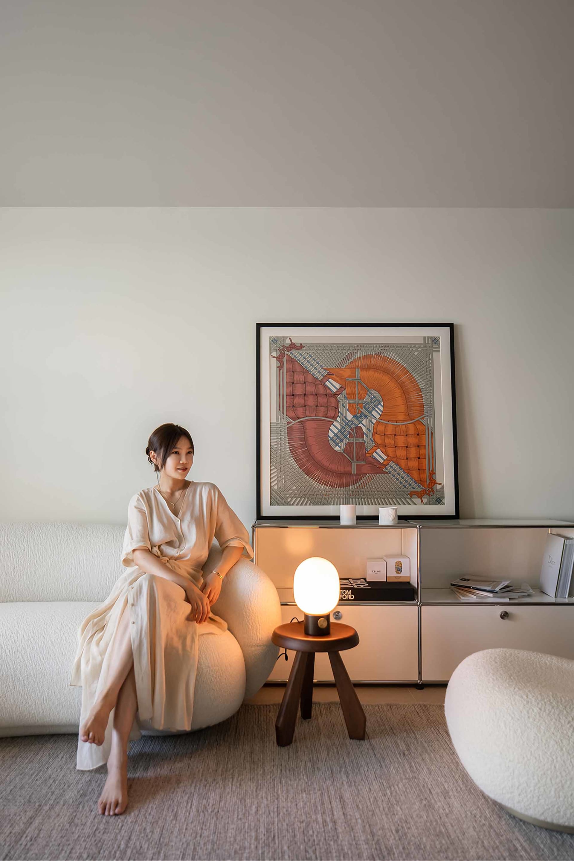 一位女士坐在極簡客廳裡的現代白色柔軟椅子上。