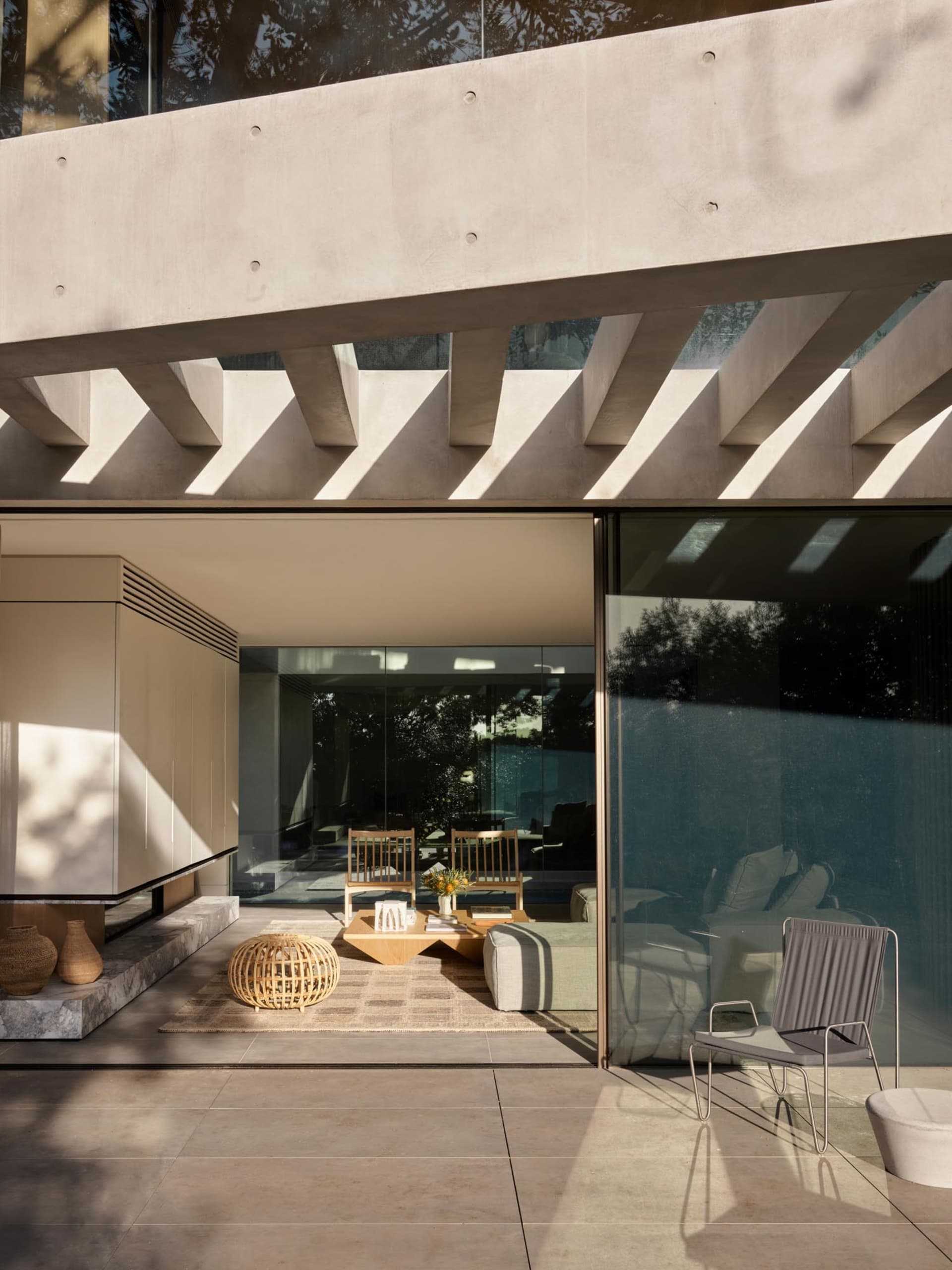 An outdoor living area featuring a concrete structure, glass walls, and modern furniture.