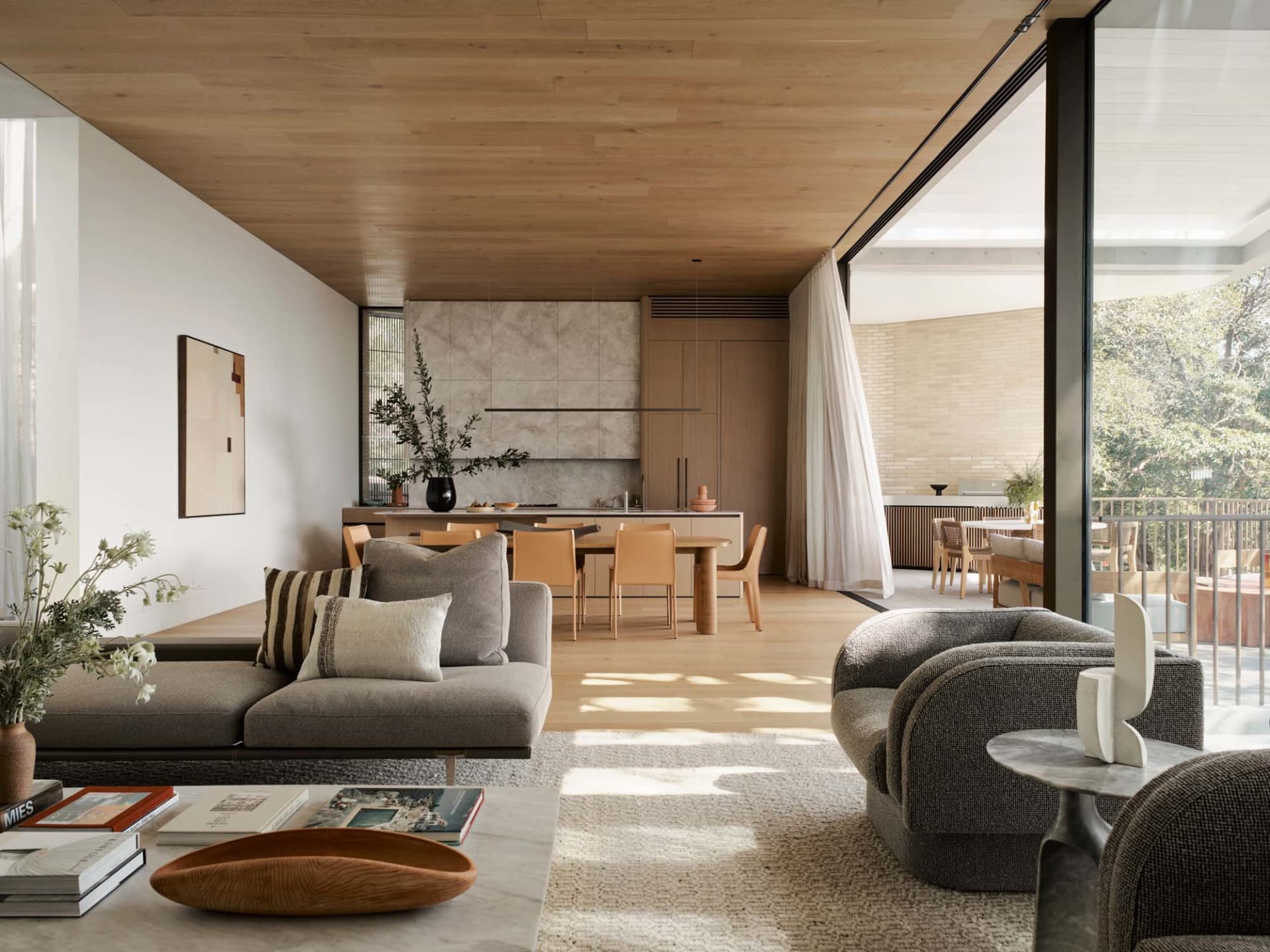 Modern minimalist living room with wood accents, featuring a comfortable couch, coffee table, and dining area with chairs aro