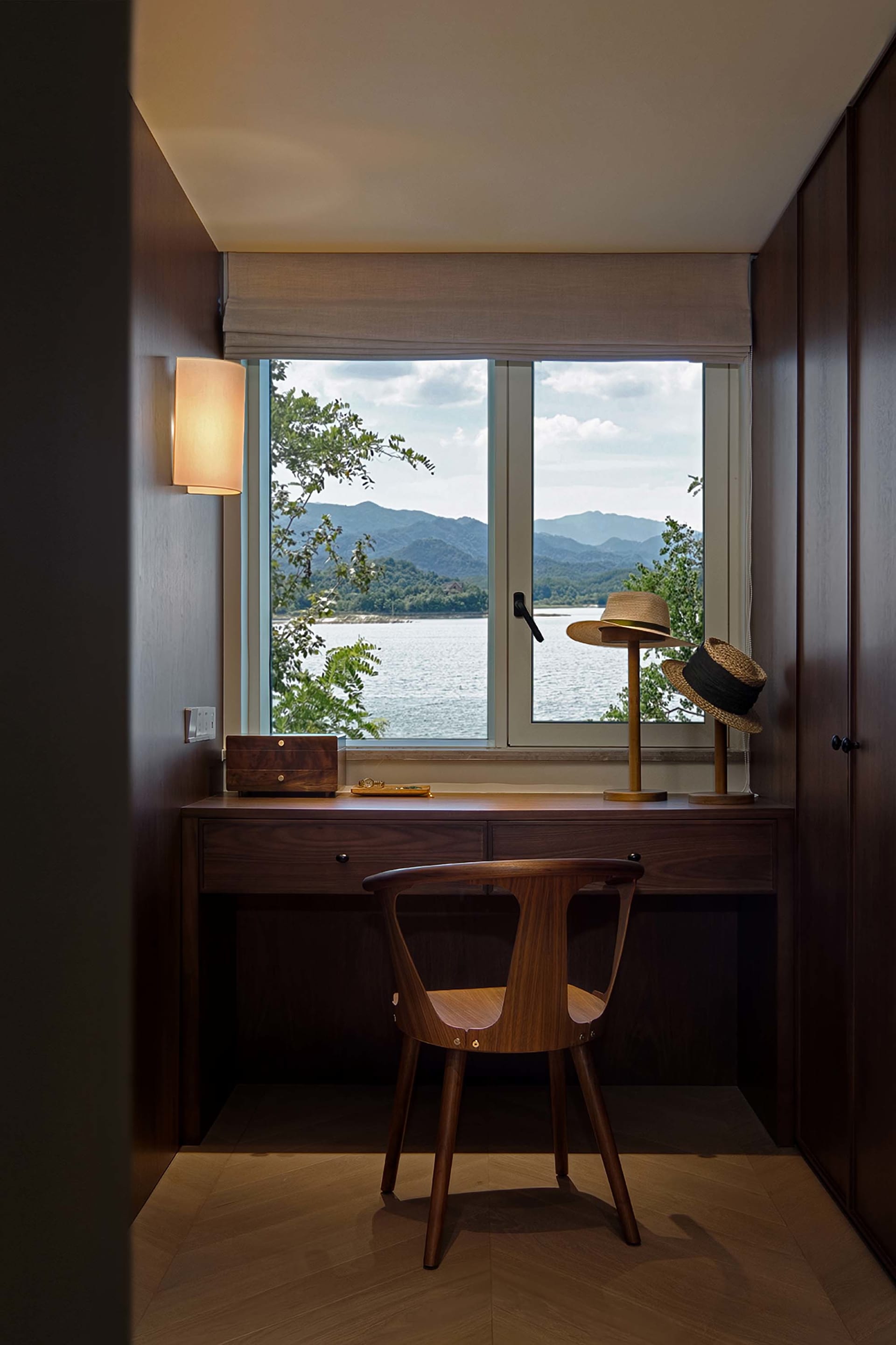 現代住宅空間,窗外可見寧靜湖景,搭配木質家具與木製桌燈。