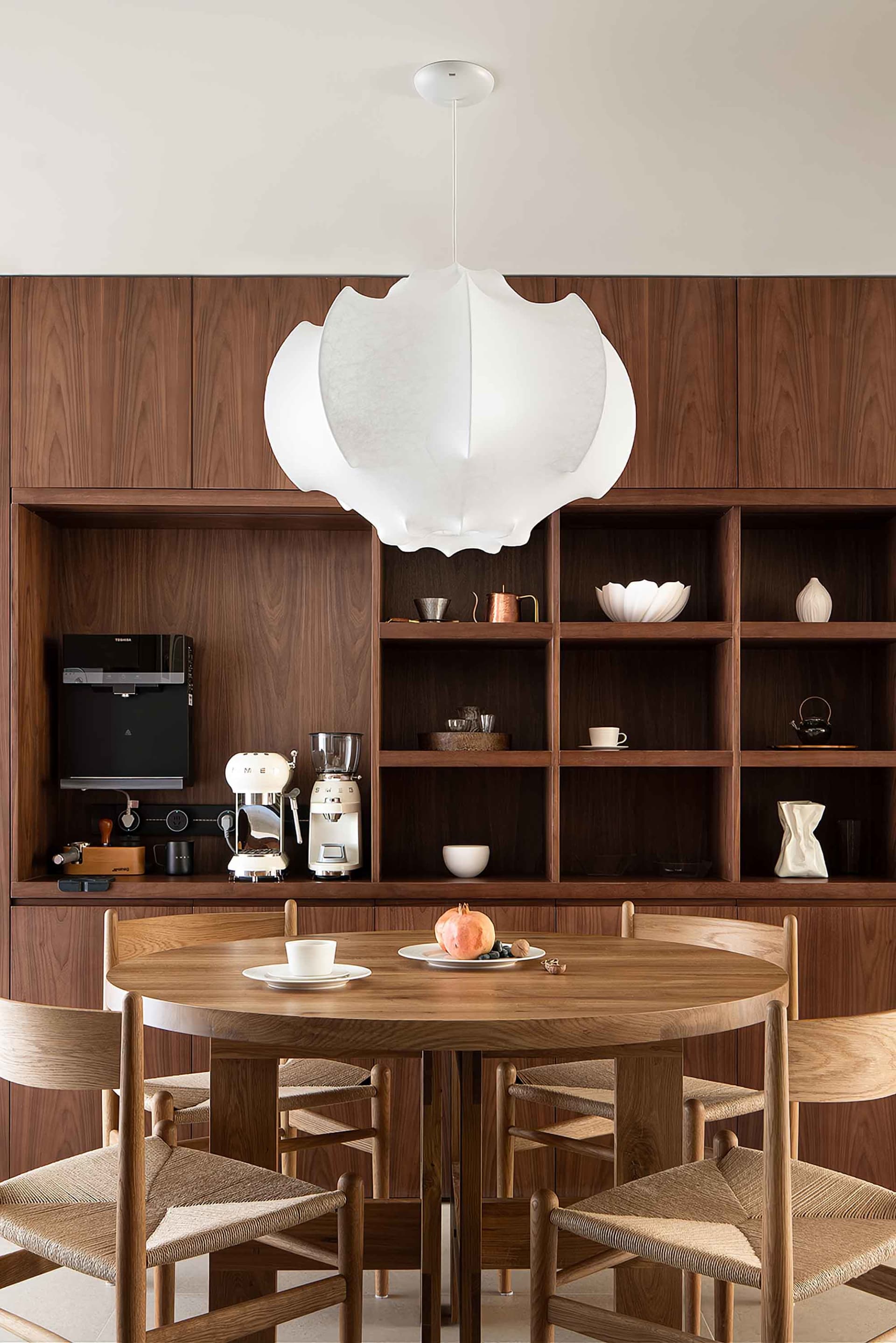 A modern residential space featuring wooden furniture and a large pendant light.