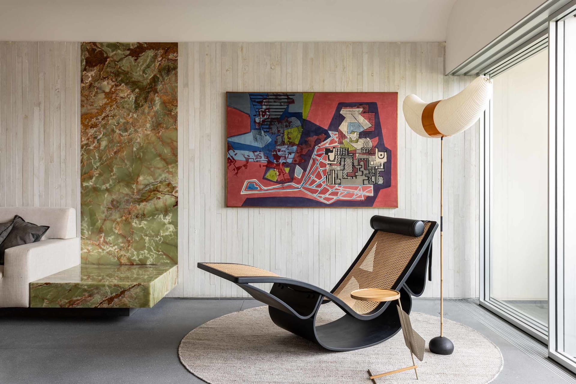 A modern living room featuring a statement marble floor lamp and abstract artwork on the wall