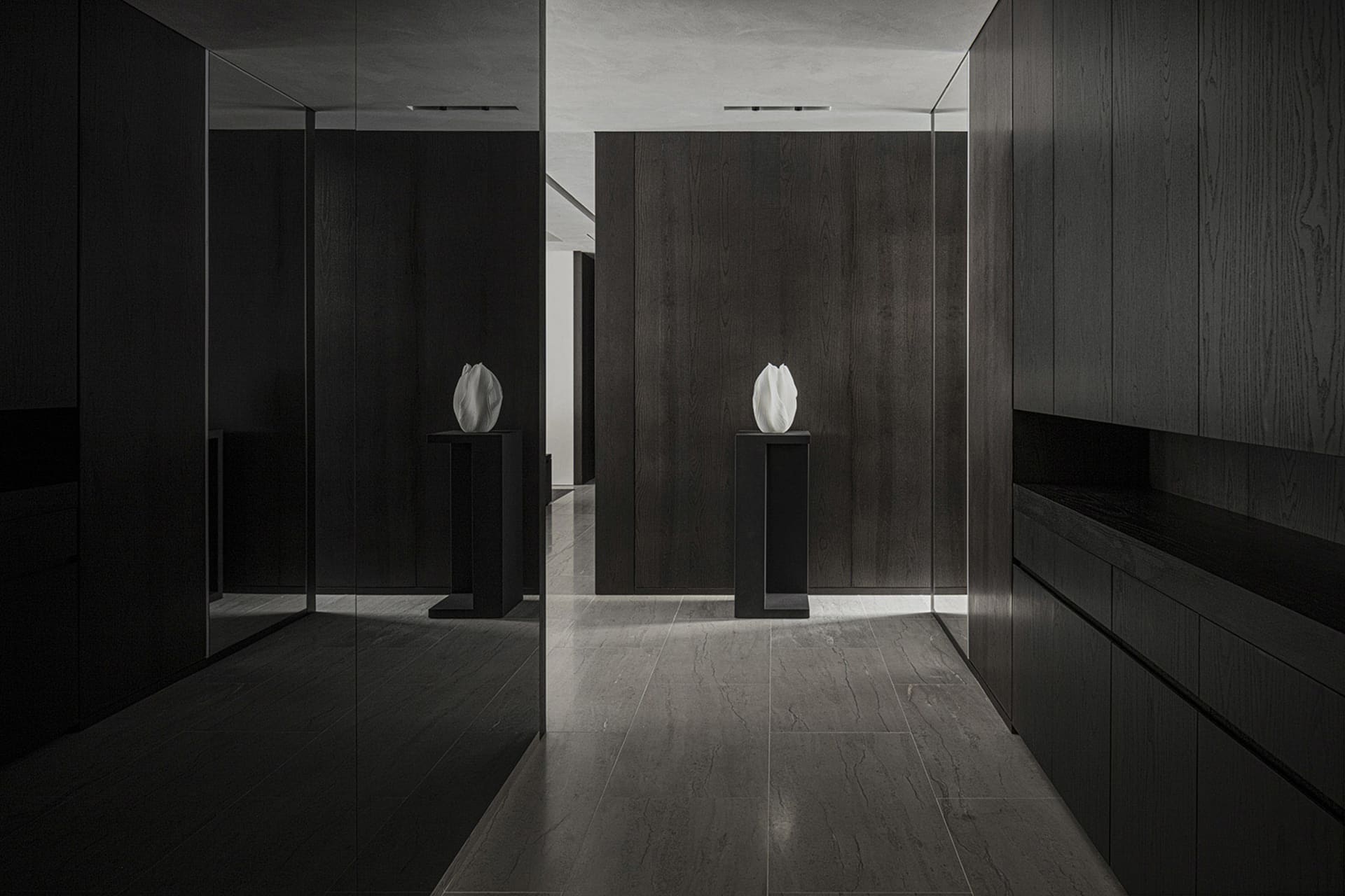 A minimalist entryway featuring dark wood and leather materials.