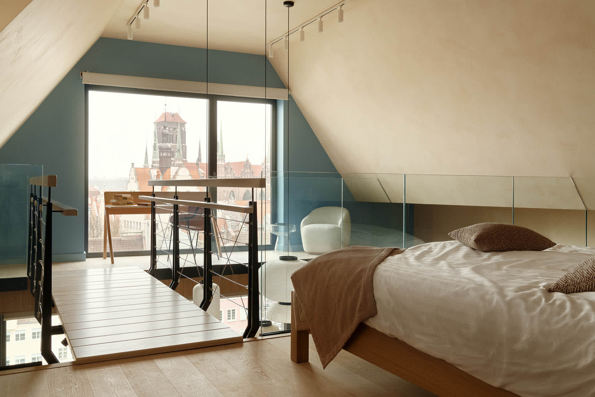 Modern bedroom featuring wooden furniture and a glass balcony overlooking a cityscape.