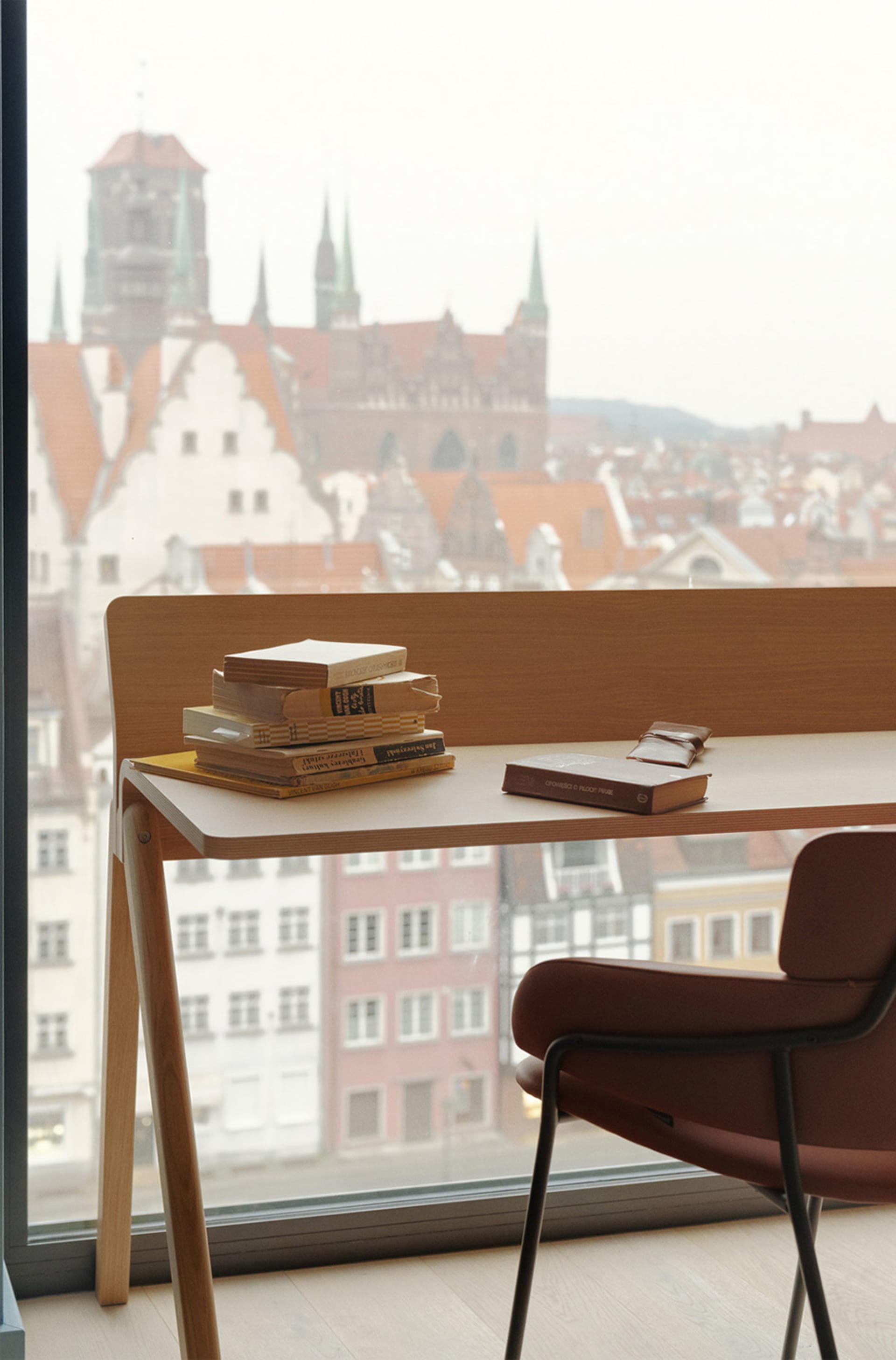 A modern study space featuring a wooden desk, a chair, and books against the backdrop of a cityscape.