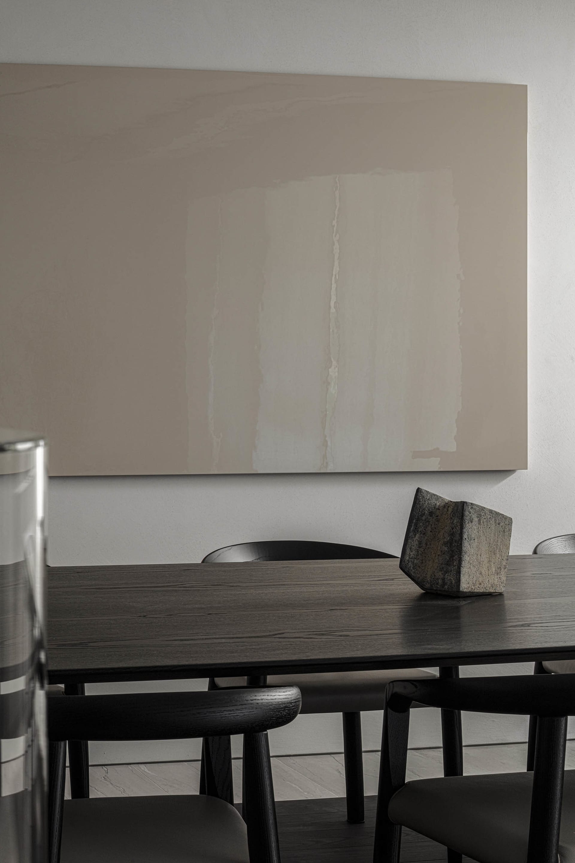 Modern dining table with wood finish and black chairs in a minimalist interior design setting.