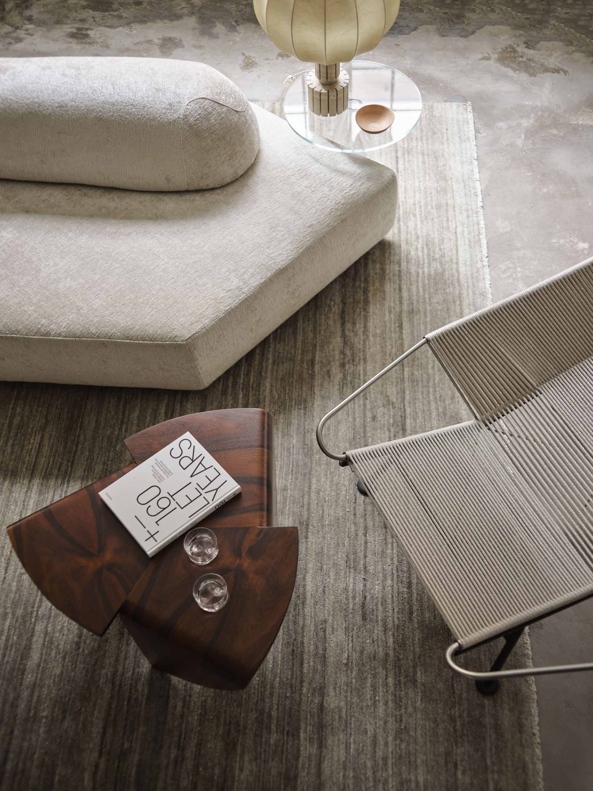 A modern living room featuring a concrete floor lamp and a wooden side table with a book and glasses on it.