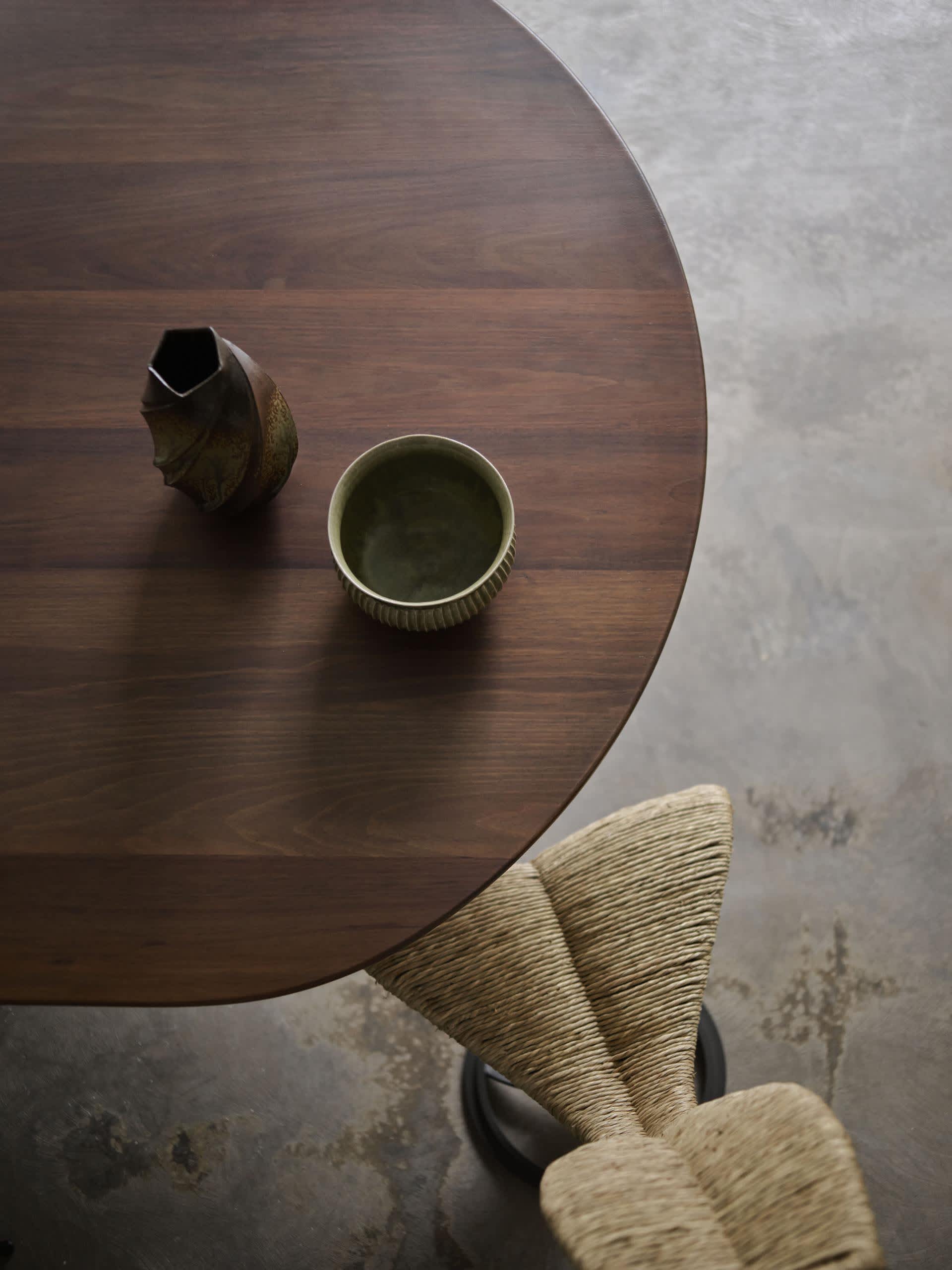 A modern wooden table with a vase and bowl on it, viewed from above.