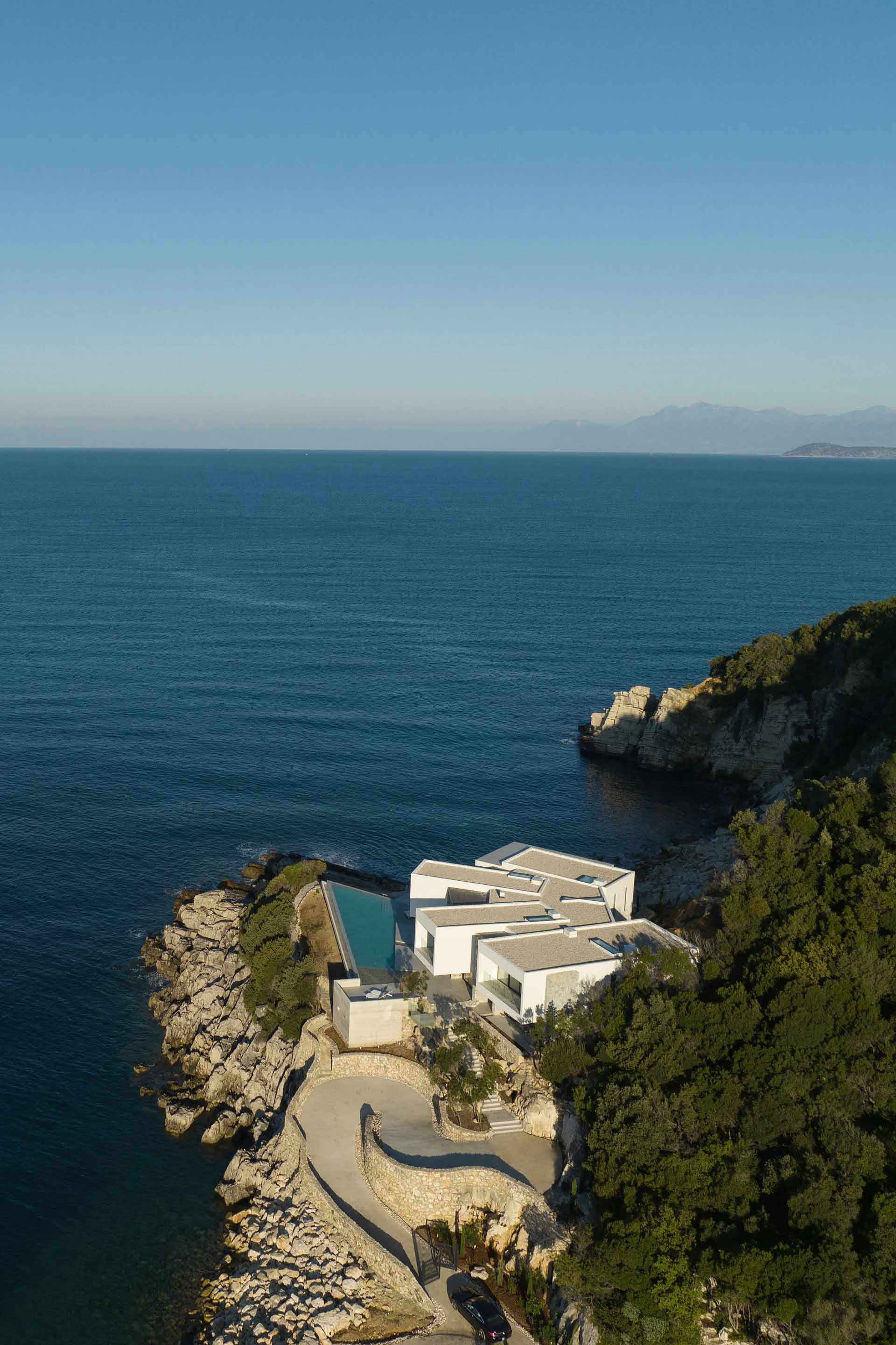 A modern house with concrete and glass façade overlooking the sea.