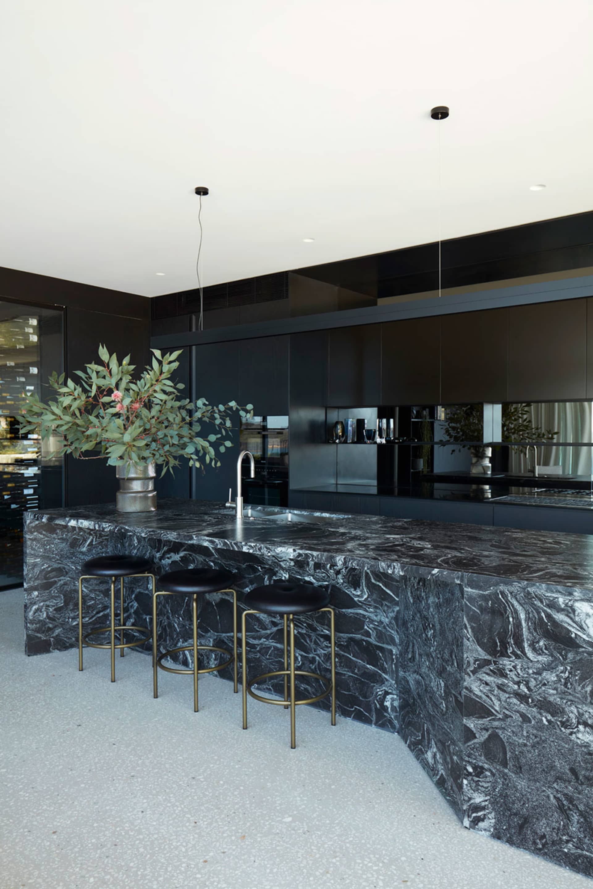 Modern industrial kitchen with black marble countertops and black stools